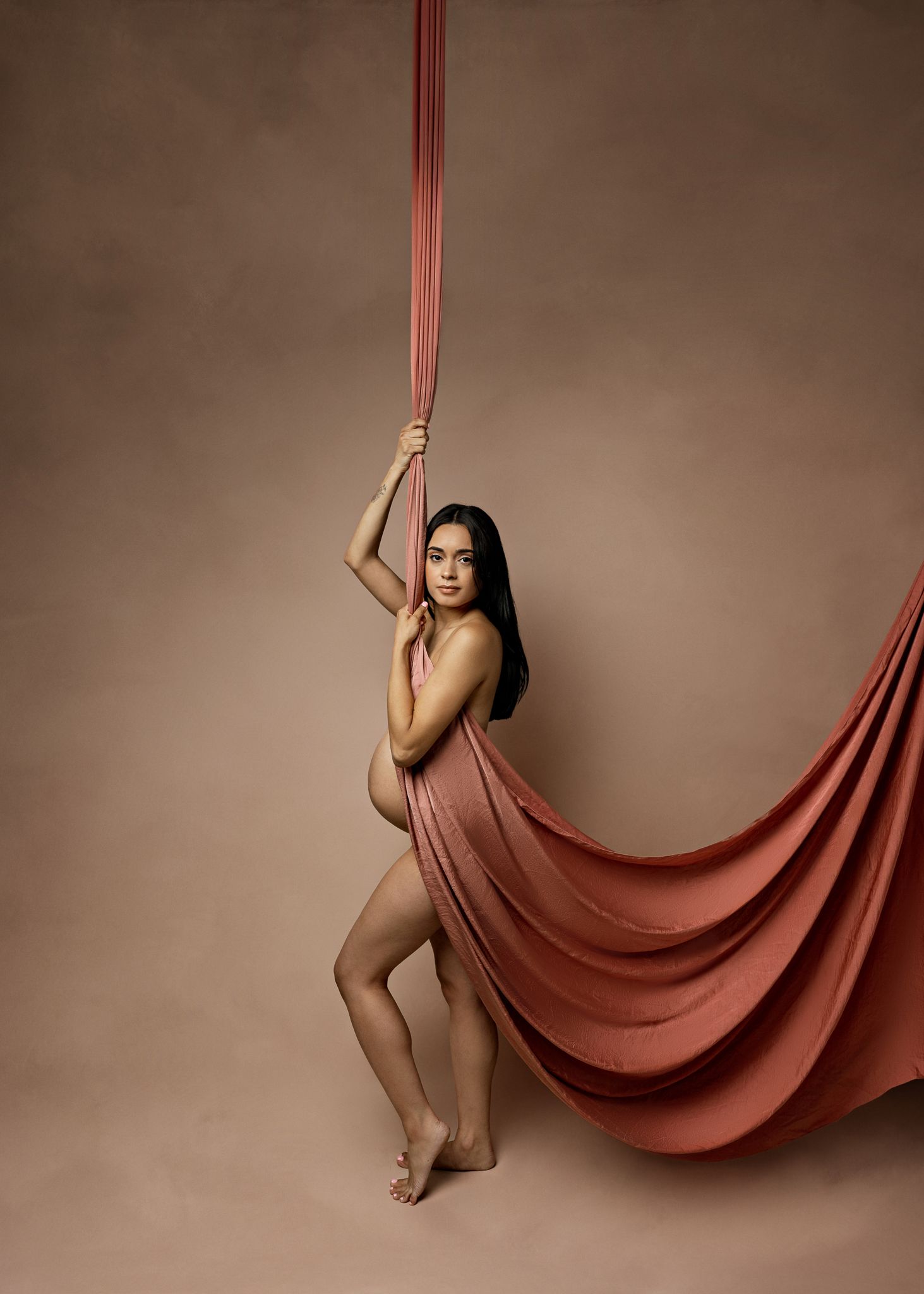 A series of artistic photos showing a figure gracefully posing with flowing red silk fabric in a studio setting.