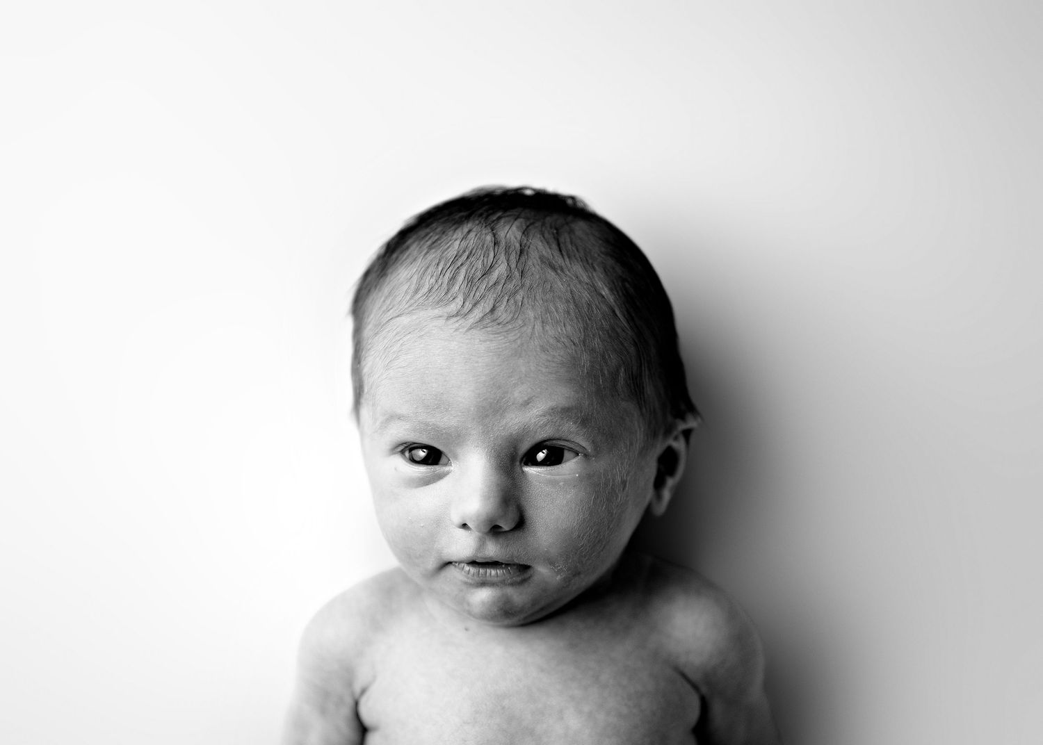 Black and white portrait series showing four different angles of a newborn baby against a white background.