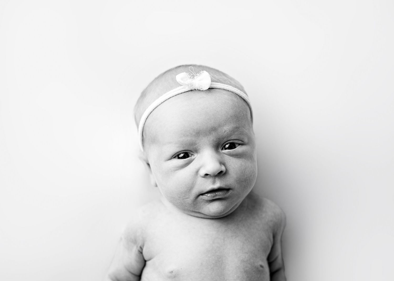 Four black and white photos of an infant wearing a white headband arranged in a horizontal row.