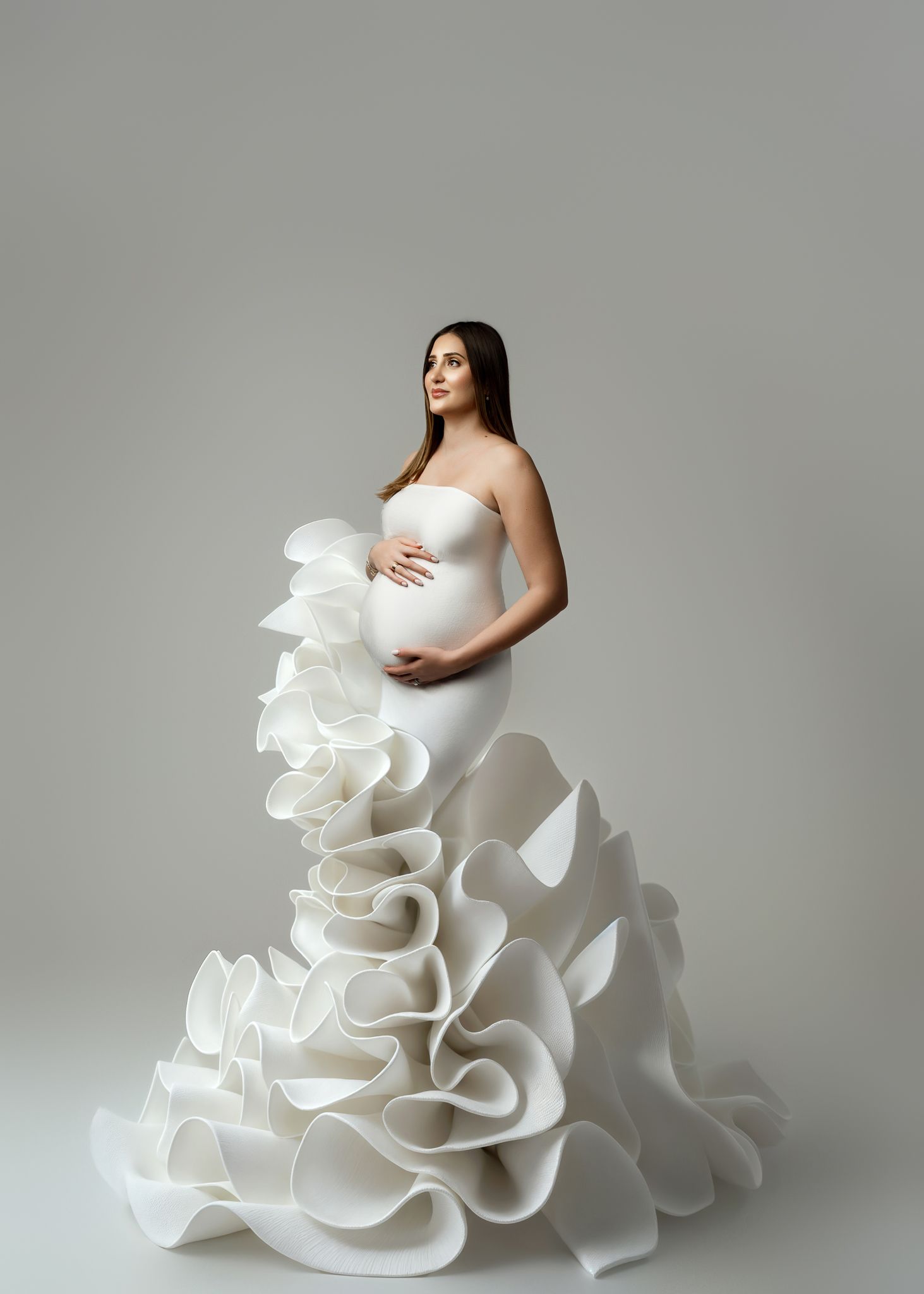 A series of fashion photographs showing a dramatic white ruffled gown against a gray studio backdrop.