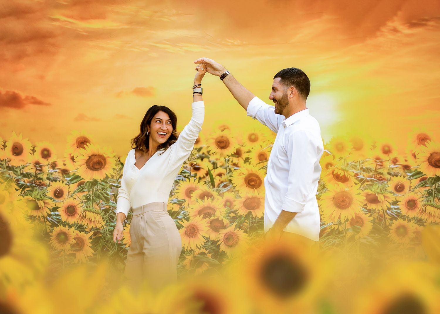 Two people dance joyfully in a sunflower field at sunset with golden light illuminating the romantic scene.