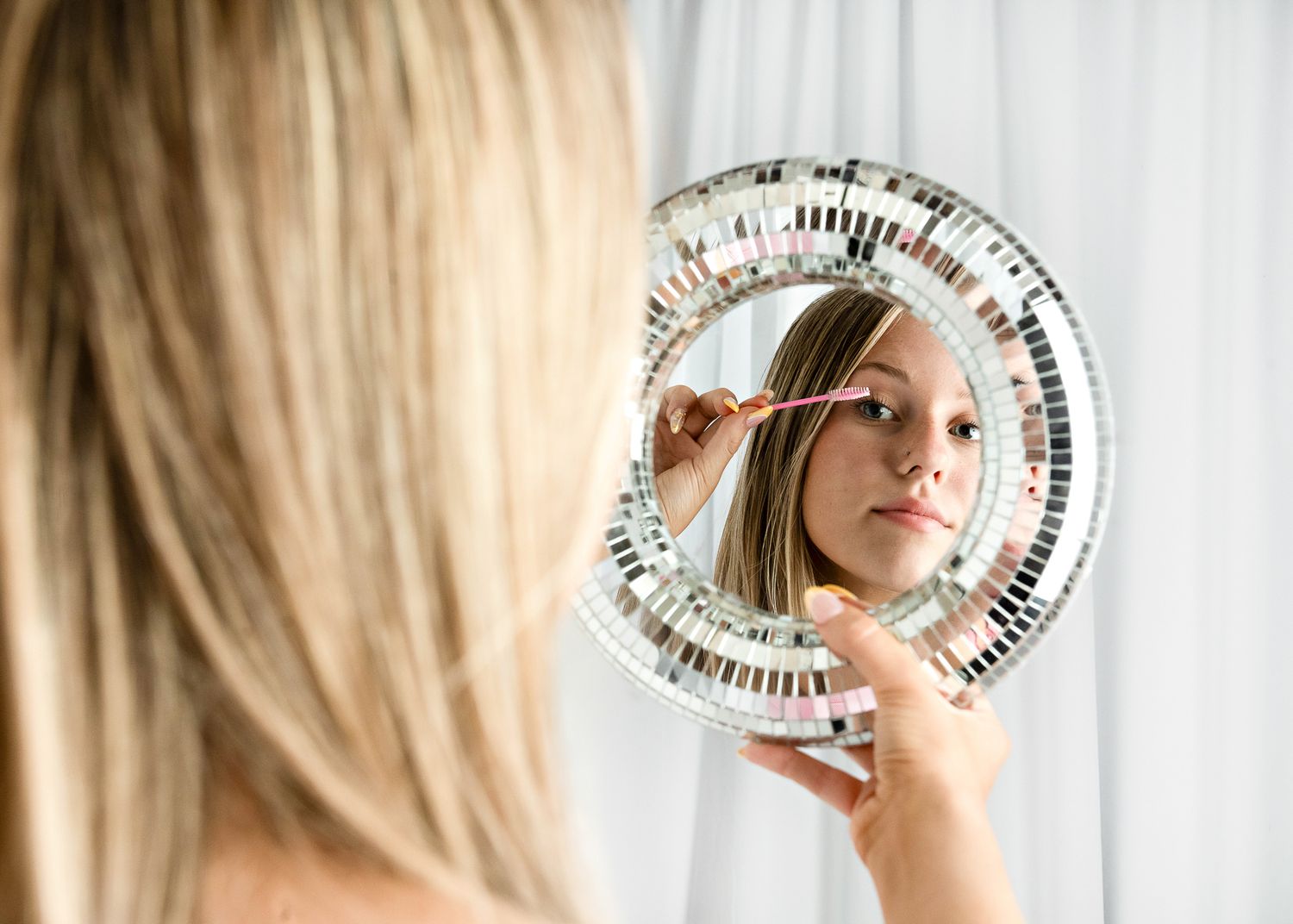 An elegant blonde woman poses in a series of portraits with a decorative round mirror.