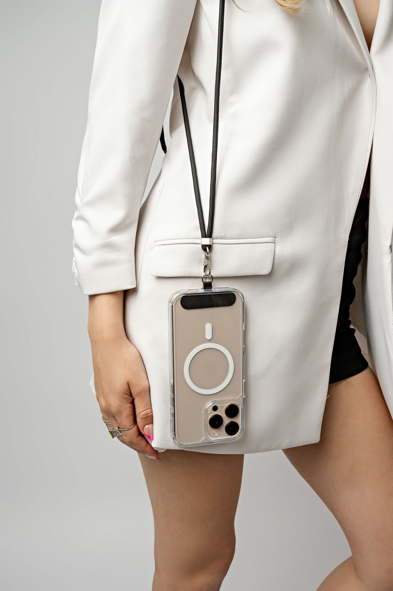 Modern white blazer styled with black shorts and a beige iPhone case with ring holder accessory.