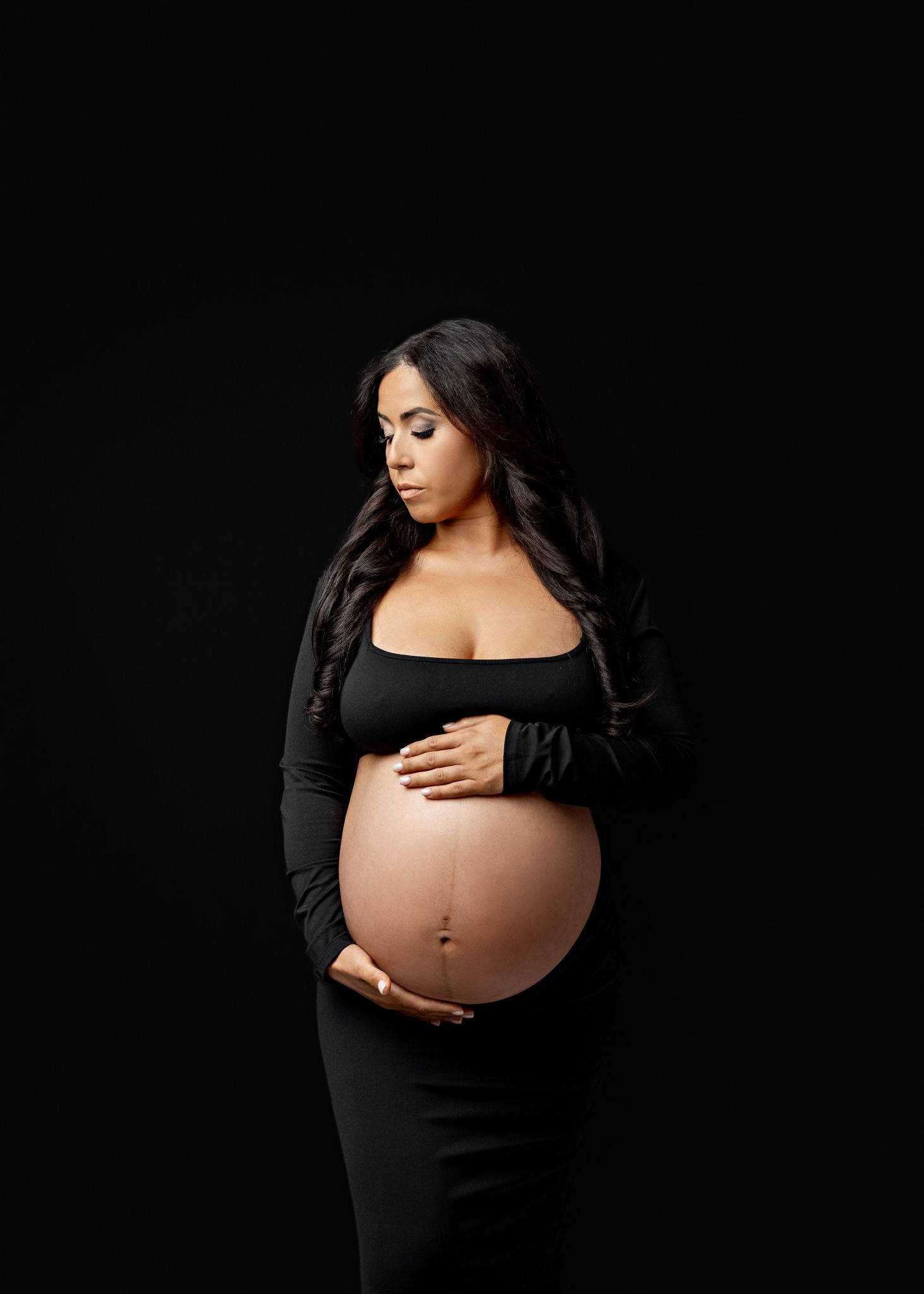 A series of maternity photos showing a pregnant woman in a black dress posing against a dark background.