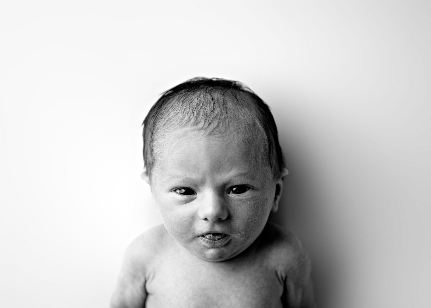Black and white portrait series of a newborn baby showing three different facial expressions.