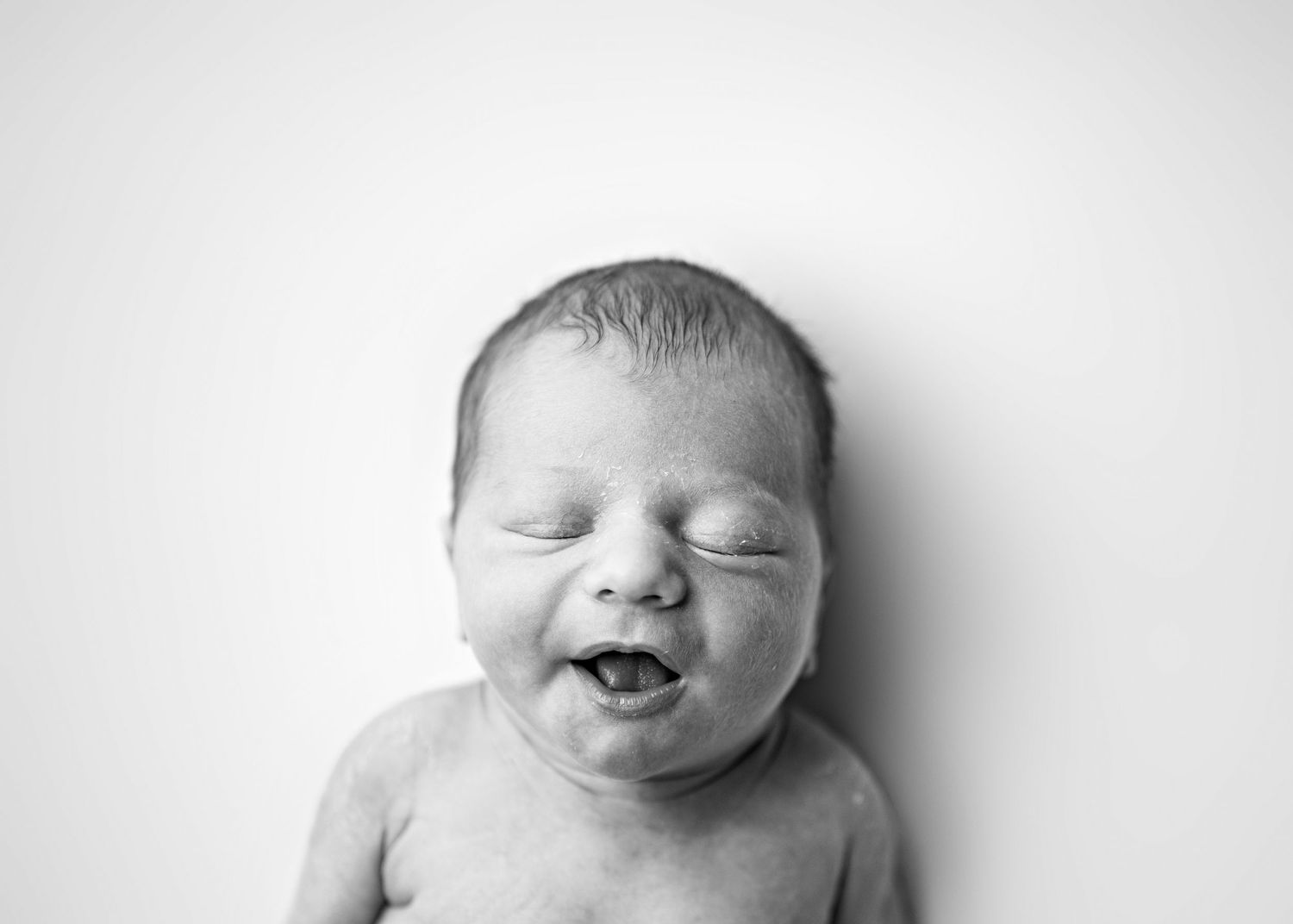Four black and white close-up photos of a sleeping newborn baby showing different facial expressions.