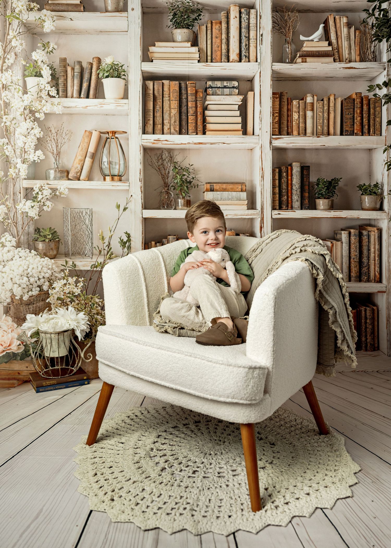 Cozy reading nook with vintage cream armchair against white bookshelves filled with antique books and potted plants.