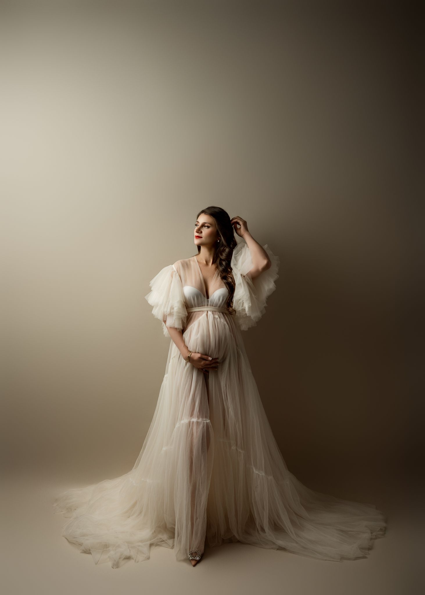 Ethereal bridal portraits in flowing white tulle gown against neutral backdrop create romantic and dreamy atmosphere.