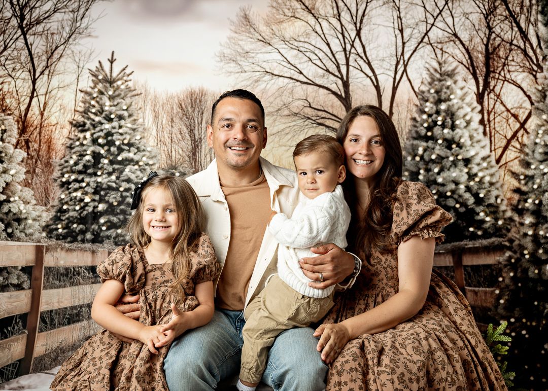 Smiling family of four in matching outfits during festive winter Christmas photo session.