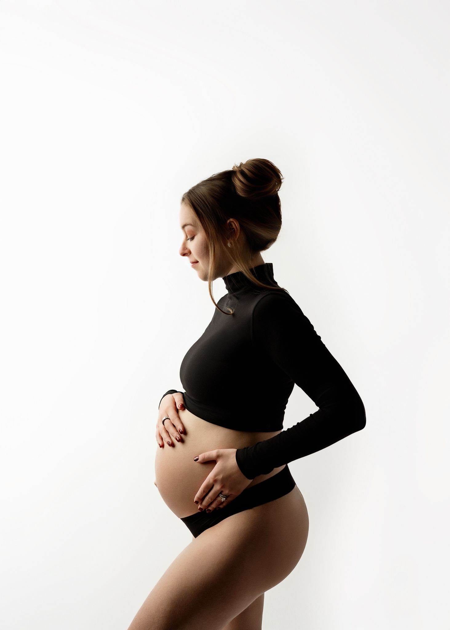 A series of four artistic maternity photos showing a pregnant woman in black against a white background.