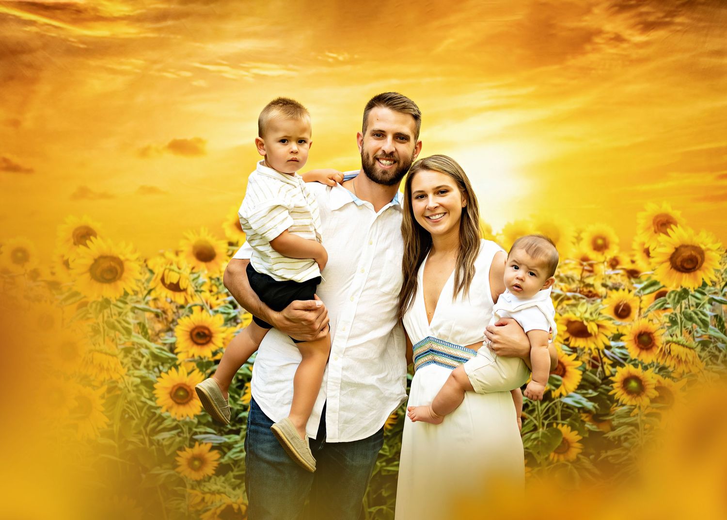 A happy-looking young family of four poses in front of a vibrant sunflower field at sunset with a golden sky backdrop.