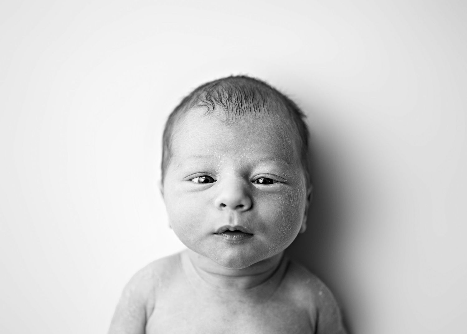 Black and white portrait series of a newborn baby showing different facial expressions.