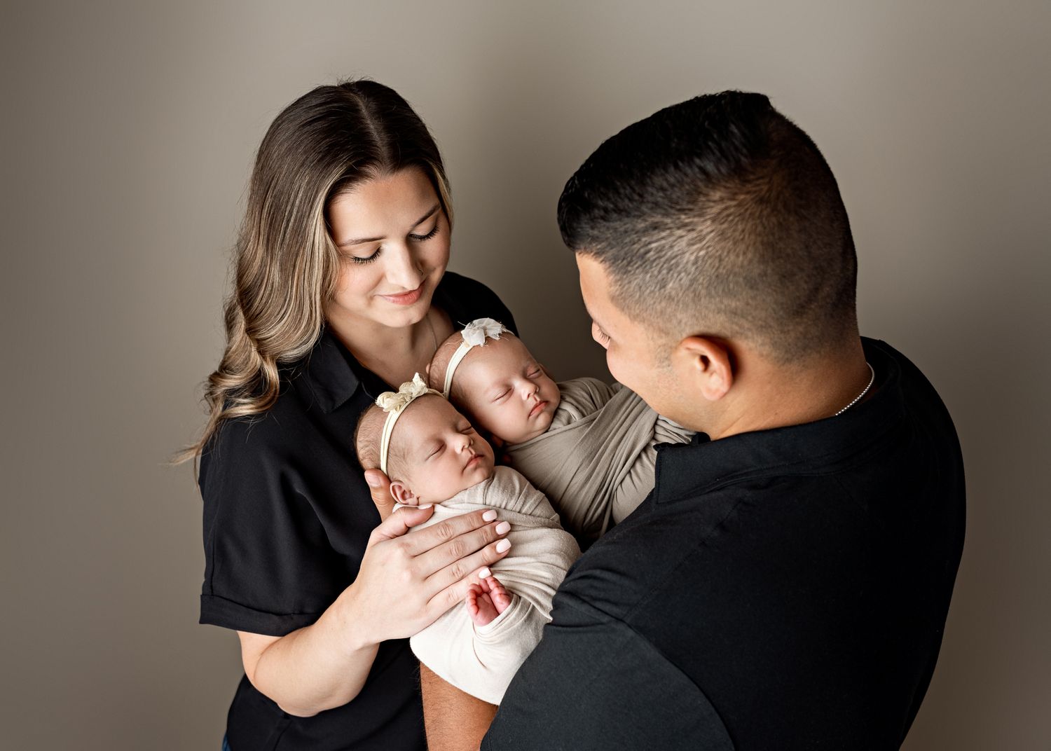 Parents sharing intimate moments with their newborn baby in a series of tender poses against grey background.