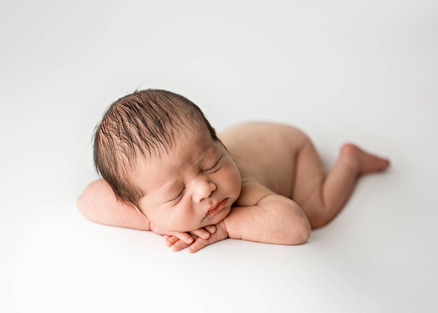 Five similar images of a sleeping newborn arranged in a horizontal row on a light backdrop.