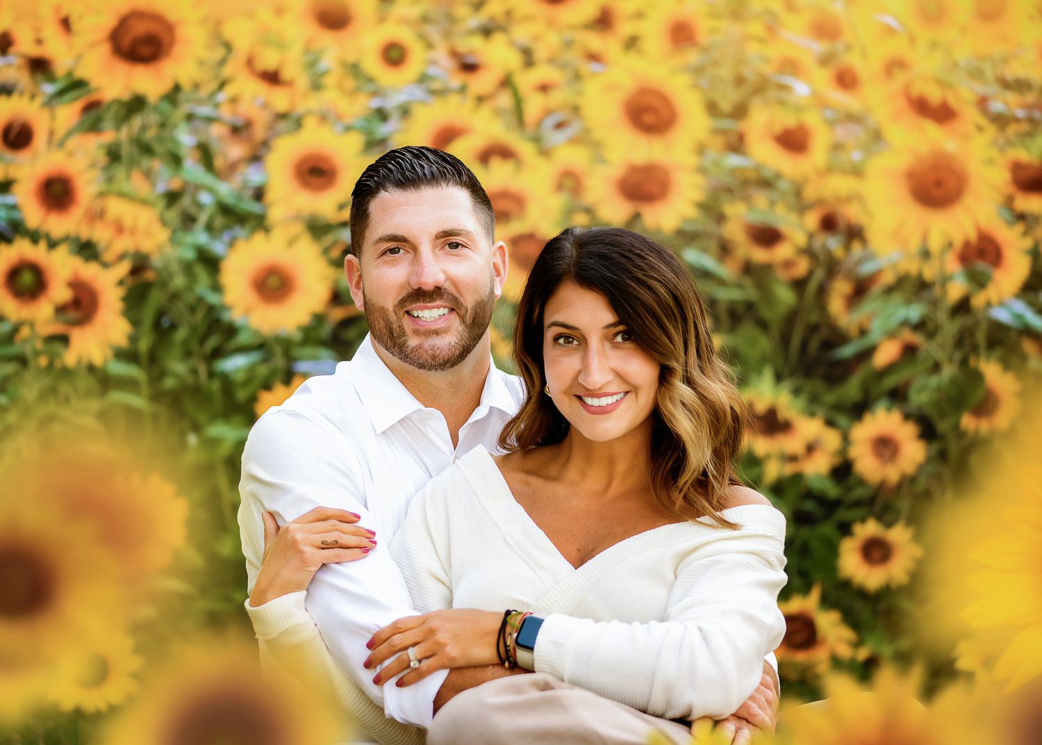 Couple posing together in a vibrant sunflower field with warm golden lighting and joyful expressions.