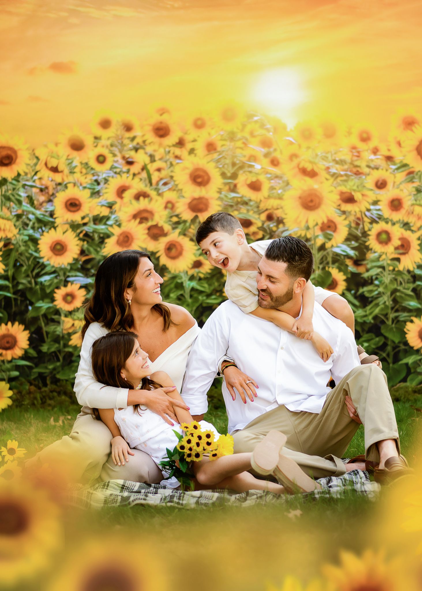 Group relaxing on picnic blanket in a blooming sunflower field during golden sunset.
