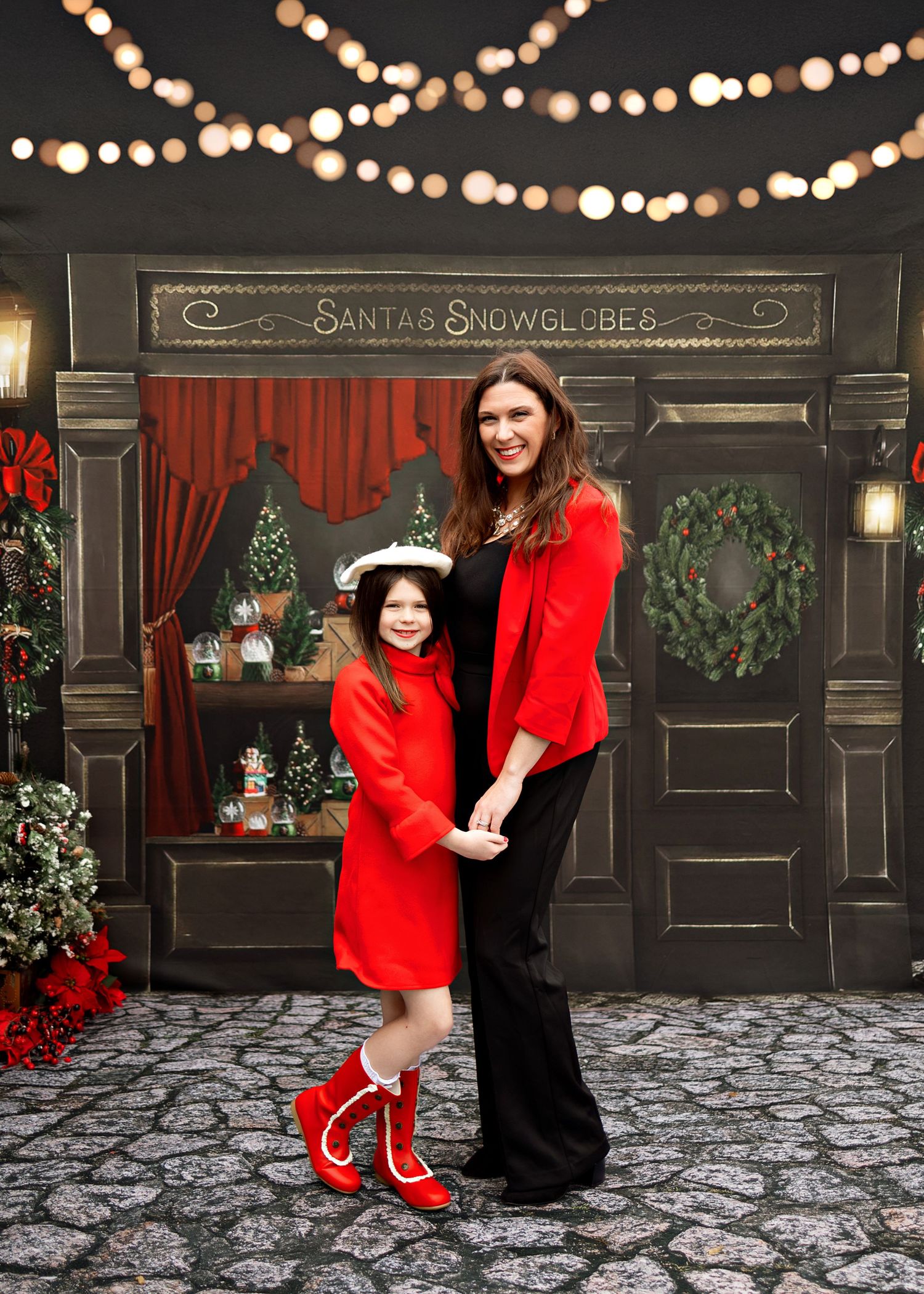 Festive holiday scene with string lights and black storefront decorated with Santa's snowglobe sign and Christmas decor.