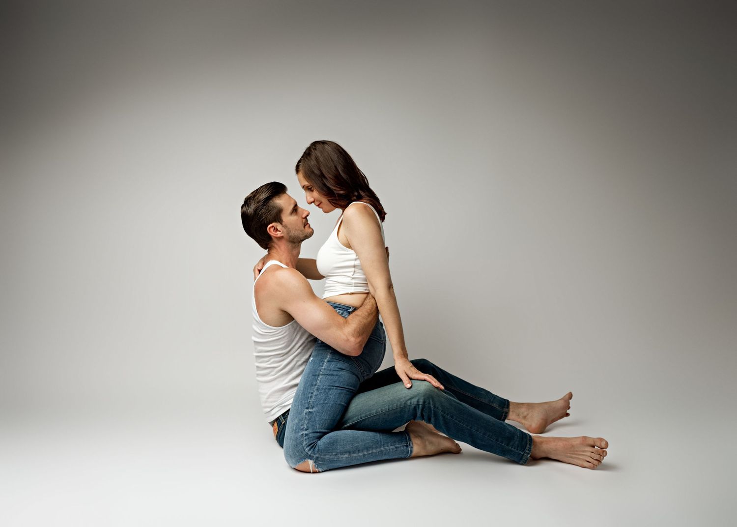 A couple in casual denim jeans and tops dance gracefully and intimately together in a professional photo studio setting.