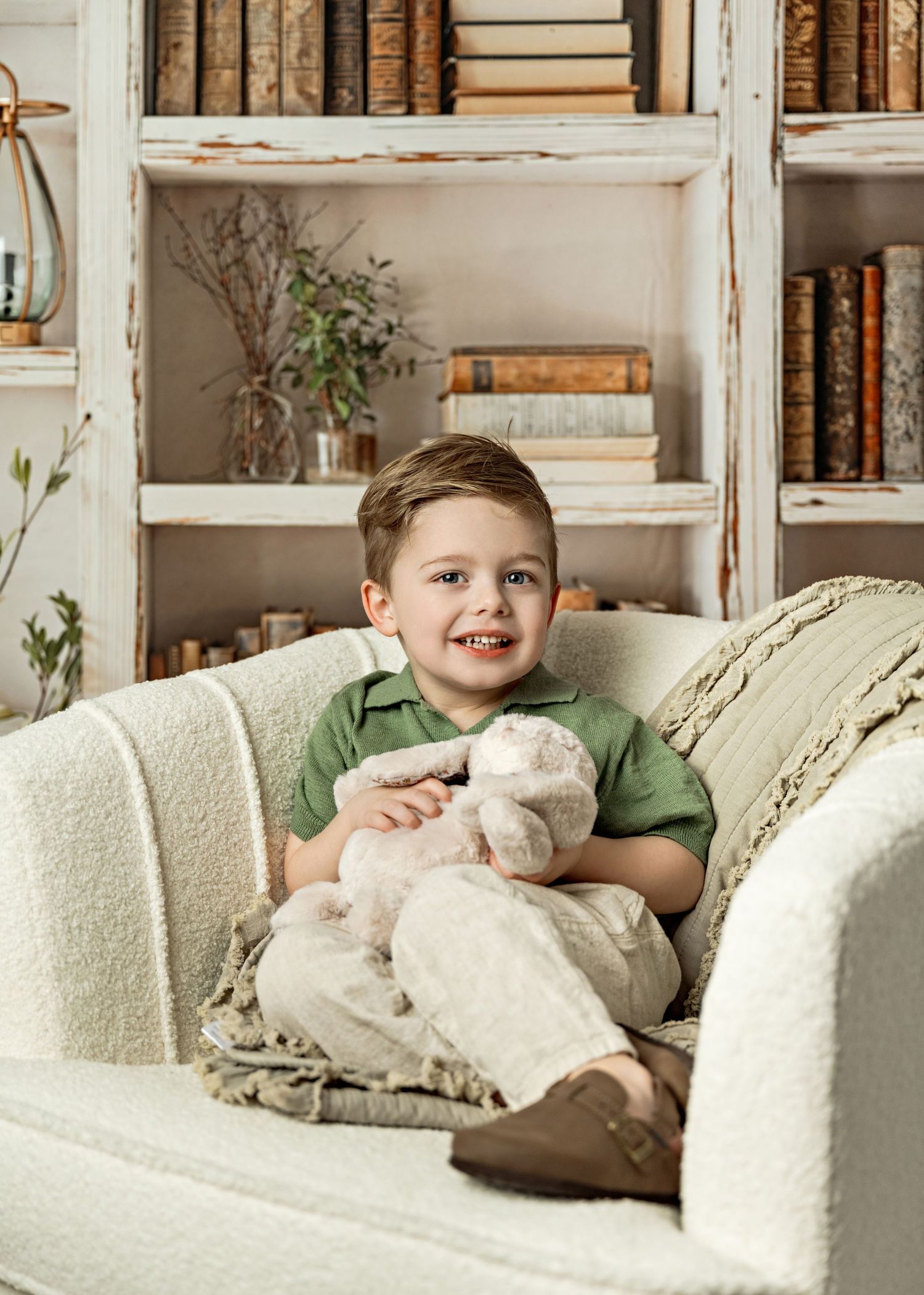 A cozy scene of someone lounging on a cream-colored couch with plush pillows and bookshelves in the background.