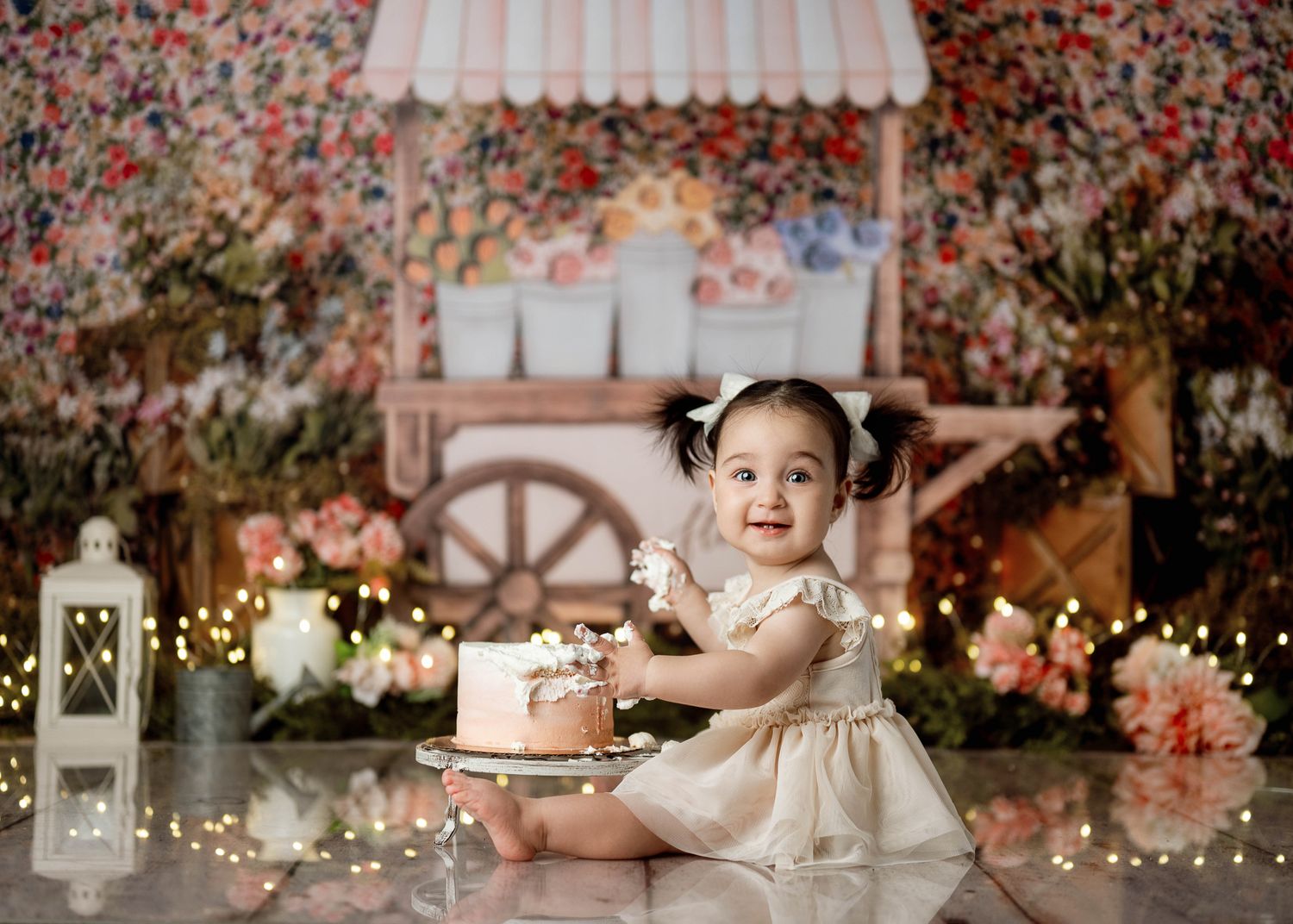 Decorated cake cart setup with pink florals and lights creates magical backdrop for special celebration photo session.