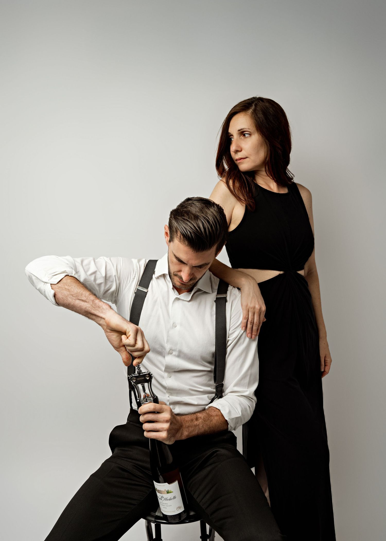 A pair in formal attire performs a dramatic dance pose sequence against a white studio background.