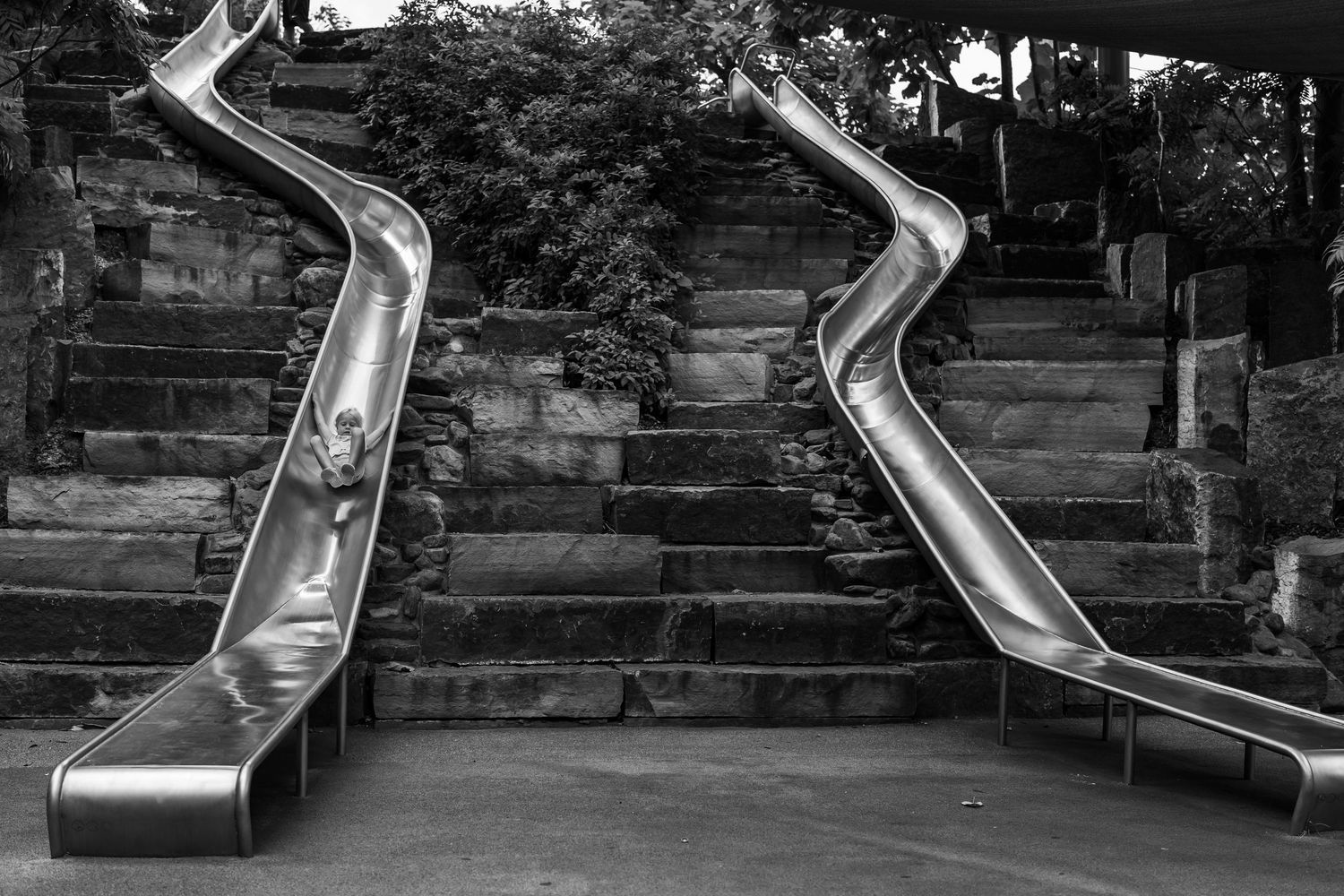 documentary family photographer captures candid image of girl sliding at Gathering Place in Tulsa Oklahoma
