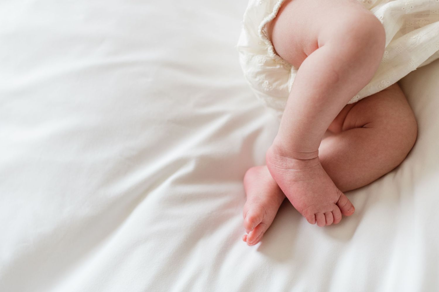 Close-up of tiny baby feet and toes wrapped in soft white blankets.