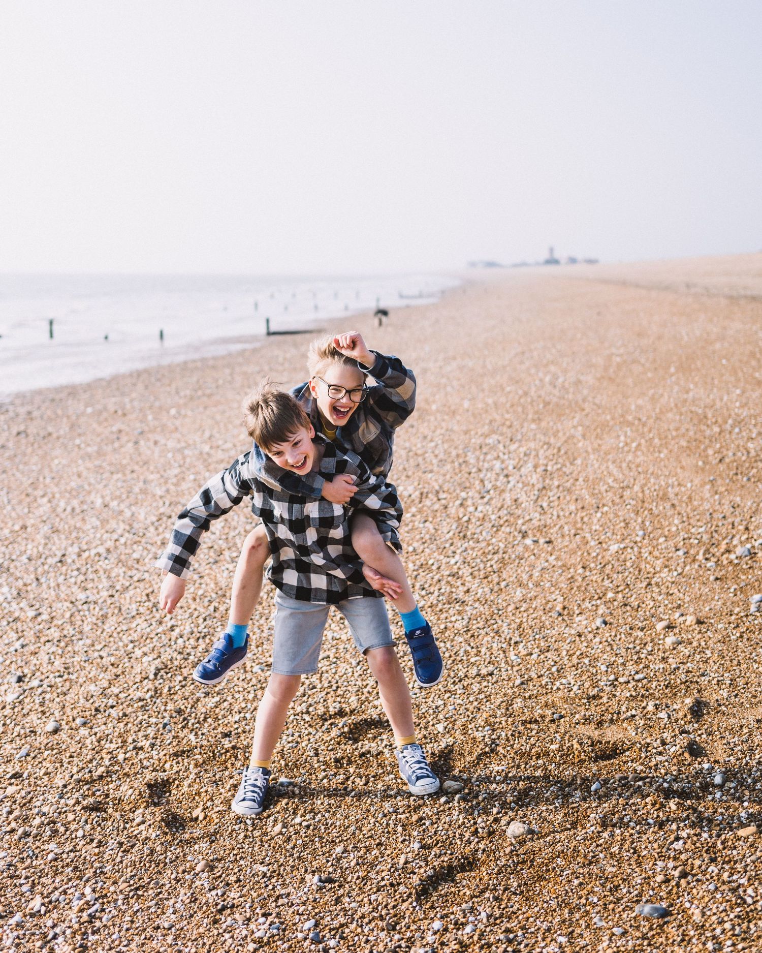 A sequence of images showing someone playfully picking up stones on a pebble beach near the ocean.