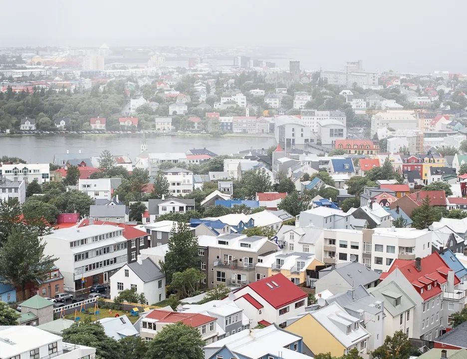 Aerial view of a coastal city with colourful houses and soft overcast light.