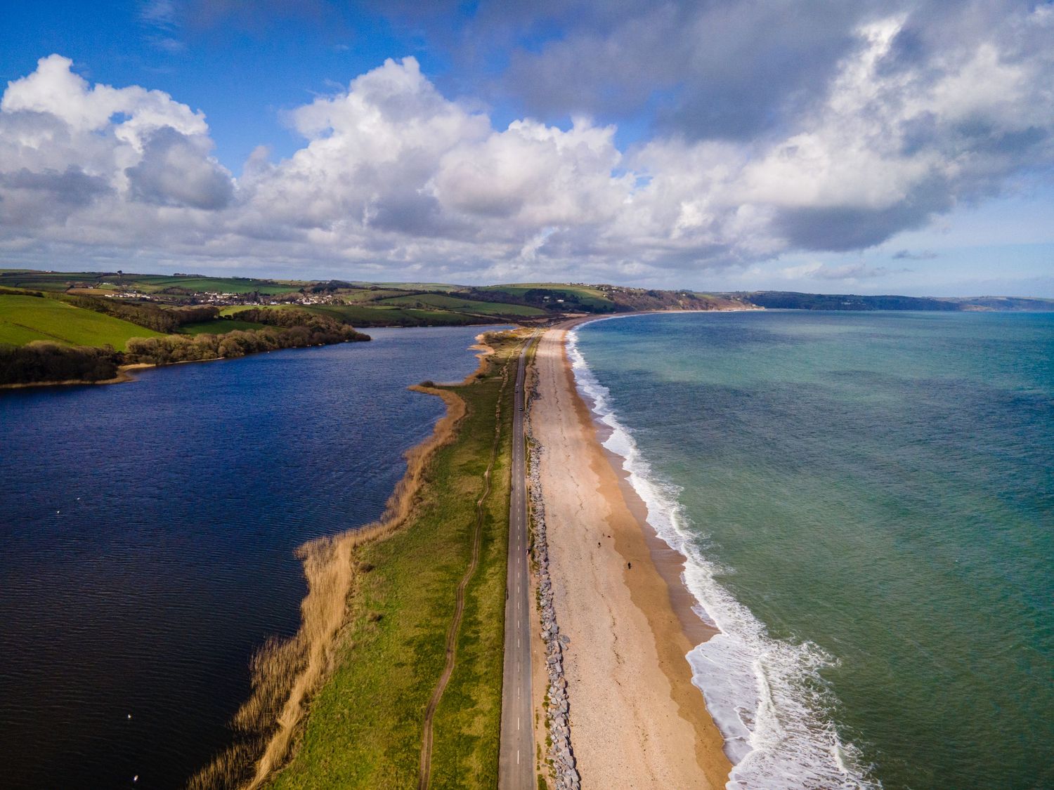 Aerial view of Chesil Beach, a narrow strip of land connecting Portland to mainland Dorset with blue waters on both sides.