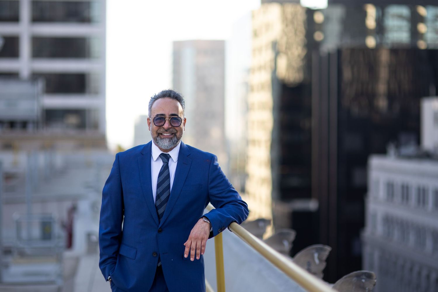 Professional in blue suit standing confidently on urban rooftop.