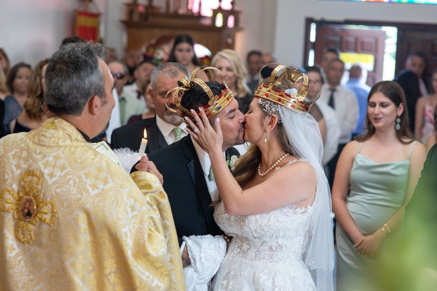 Traditional wedding ceremony with priest placing crowns on couple during Orthodox Christian service.