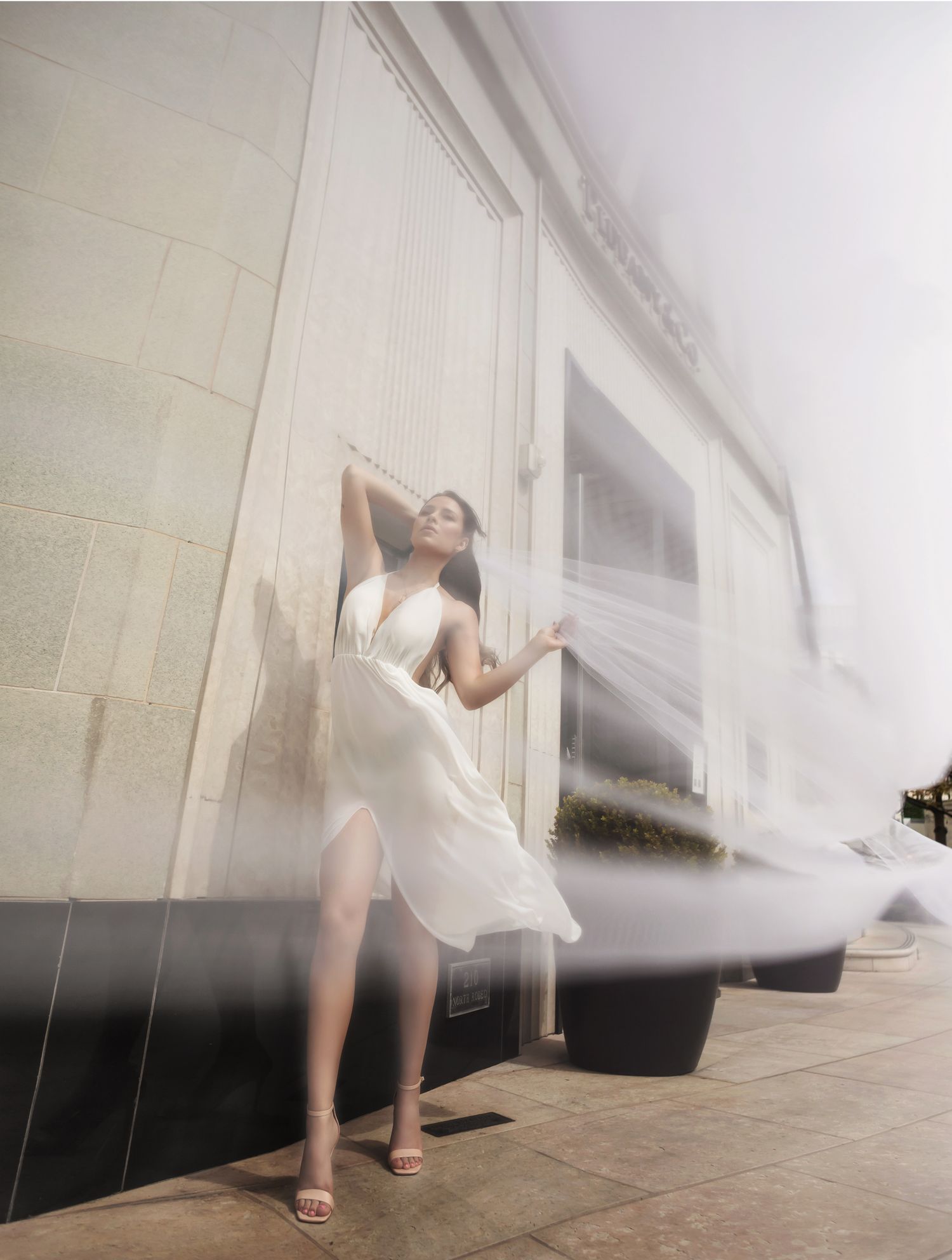 A series of ethereal photos showing a figure in white fabric moving gracefully against a light colored wall.