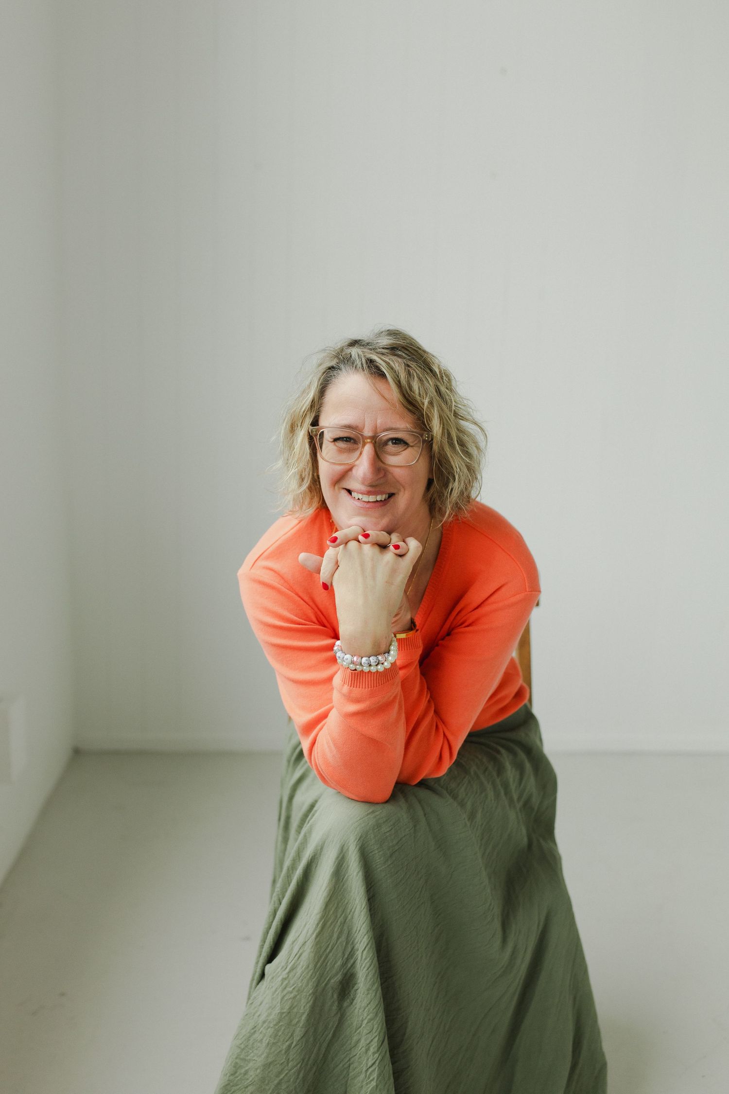 Woman posed seated with hands under chin during personal brand photoshoot in Hamilton studio