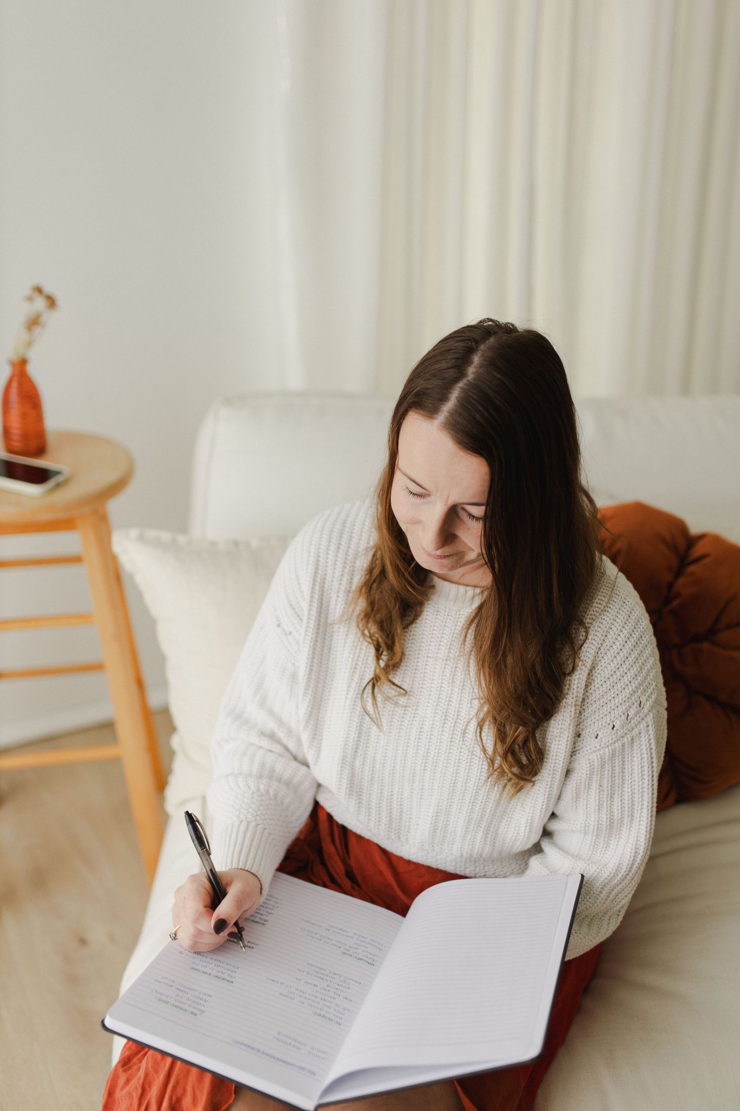 Woman looking down writing in notebook during a photoshoot in Hamilton