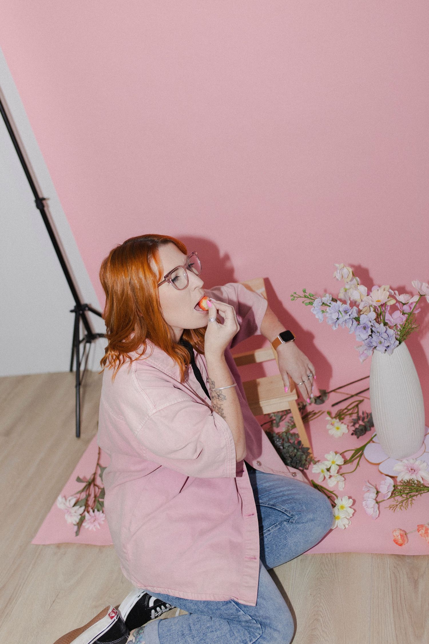 Woman wearing pink eating a strawberry during a photoshoot