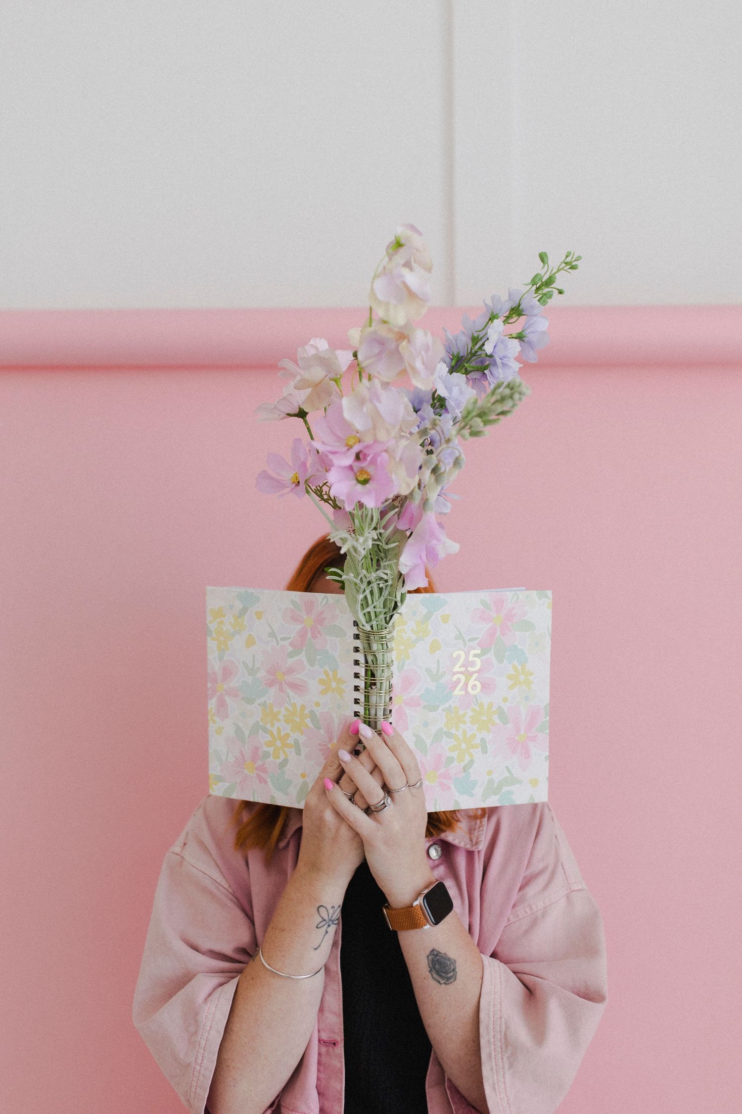 Woman holding notebook and bouquet in front of face during photoshoot in Hamilton NZ