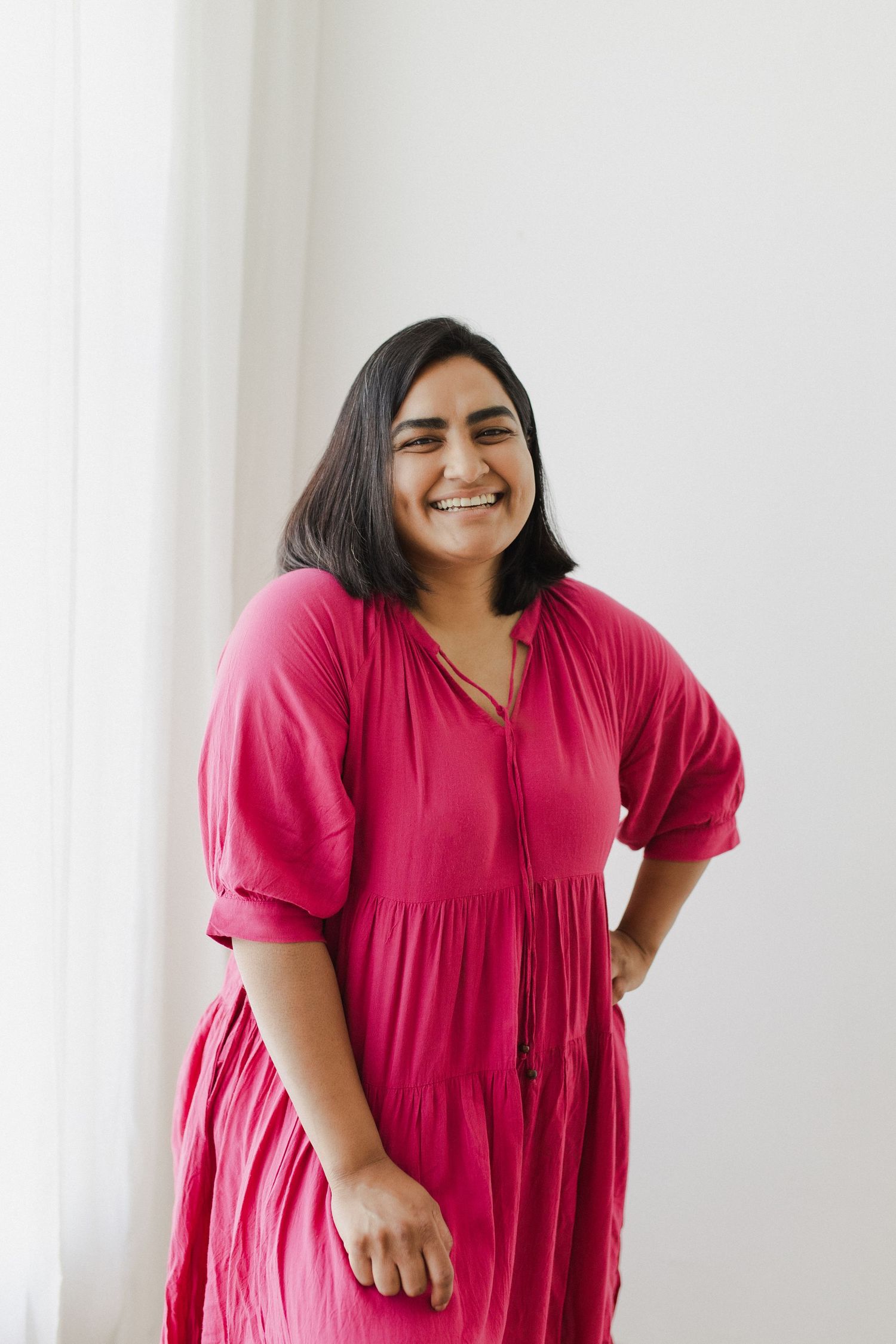 Woman wearing pink dress smiling at camera during branding photoshoot in Hamilton