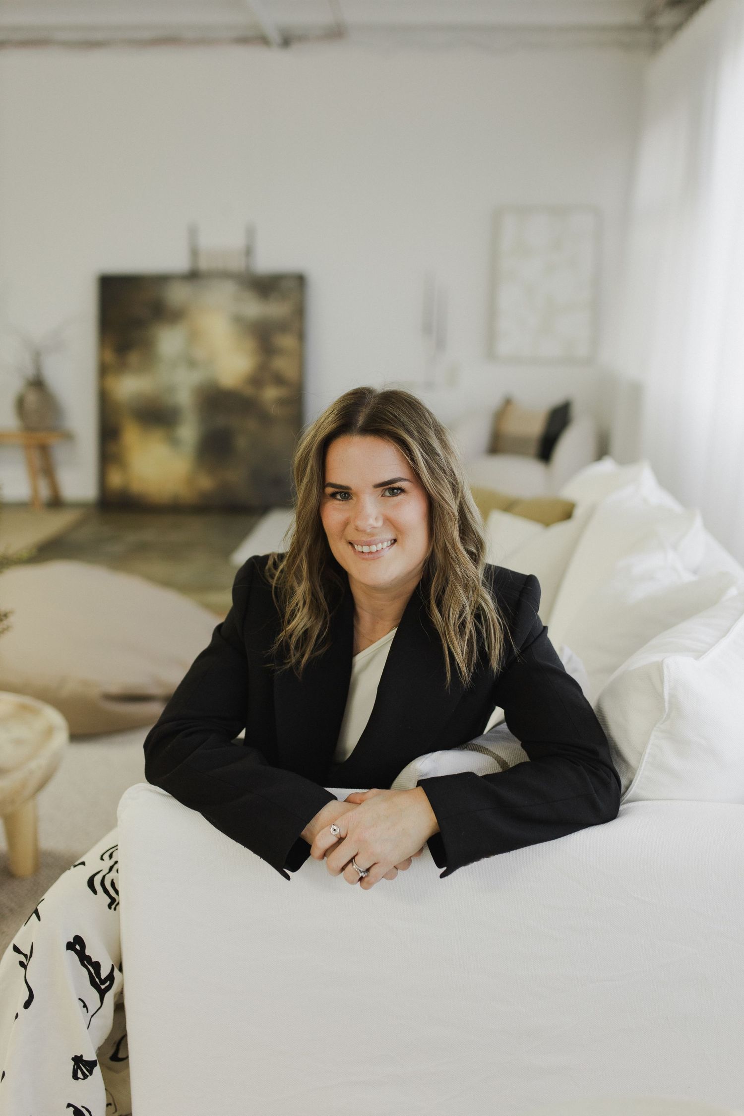 Woman seated with arms over couch during personal brand photoshoot in Hamilton studio