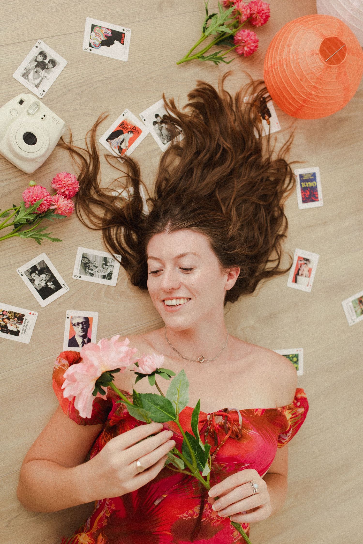 Woman laying on the floor surrounded in colourful playing cards during a creative photoshoot in Hamilton studio