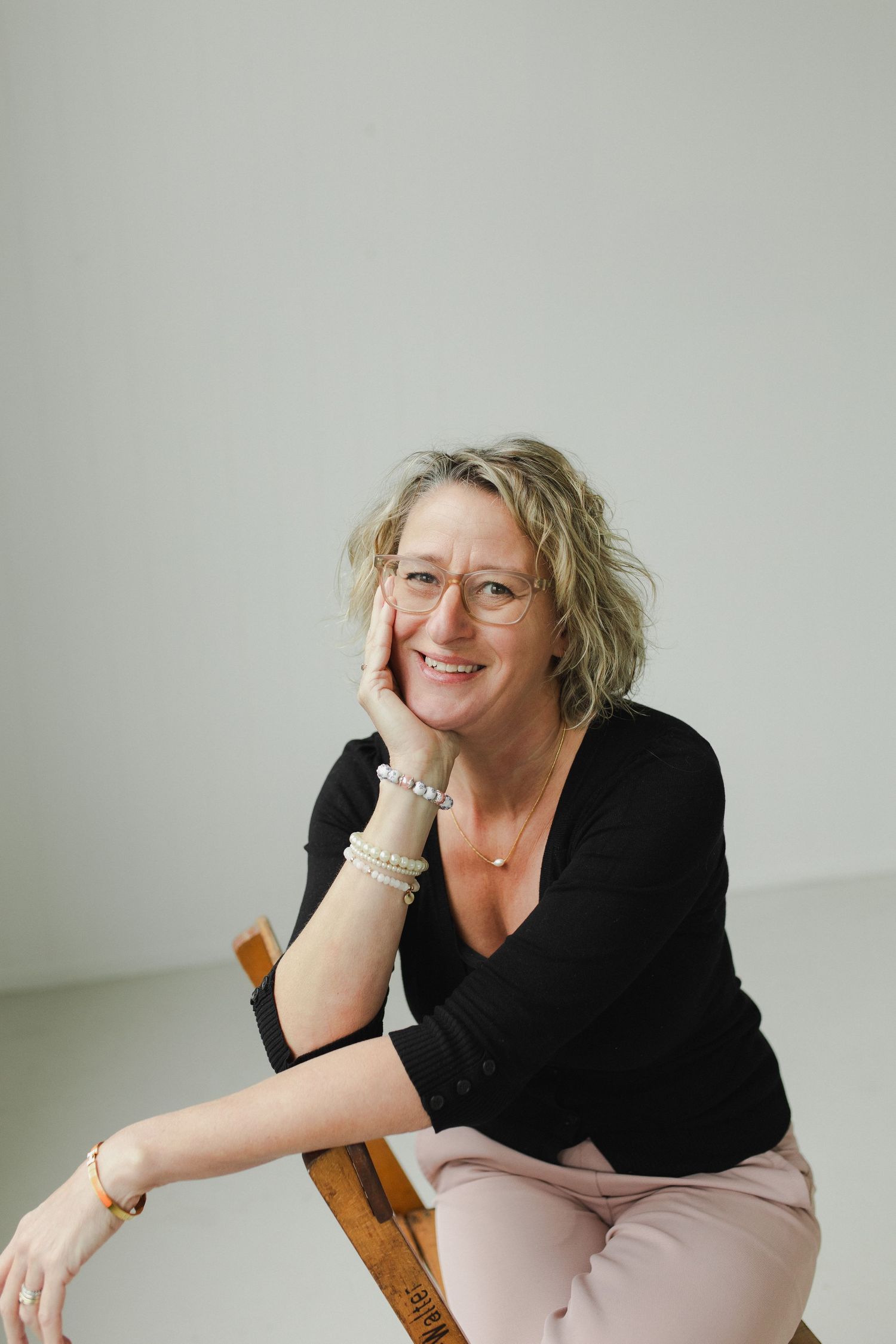 Woman posed seated with hand on cheek during personal brand photoshoot
