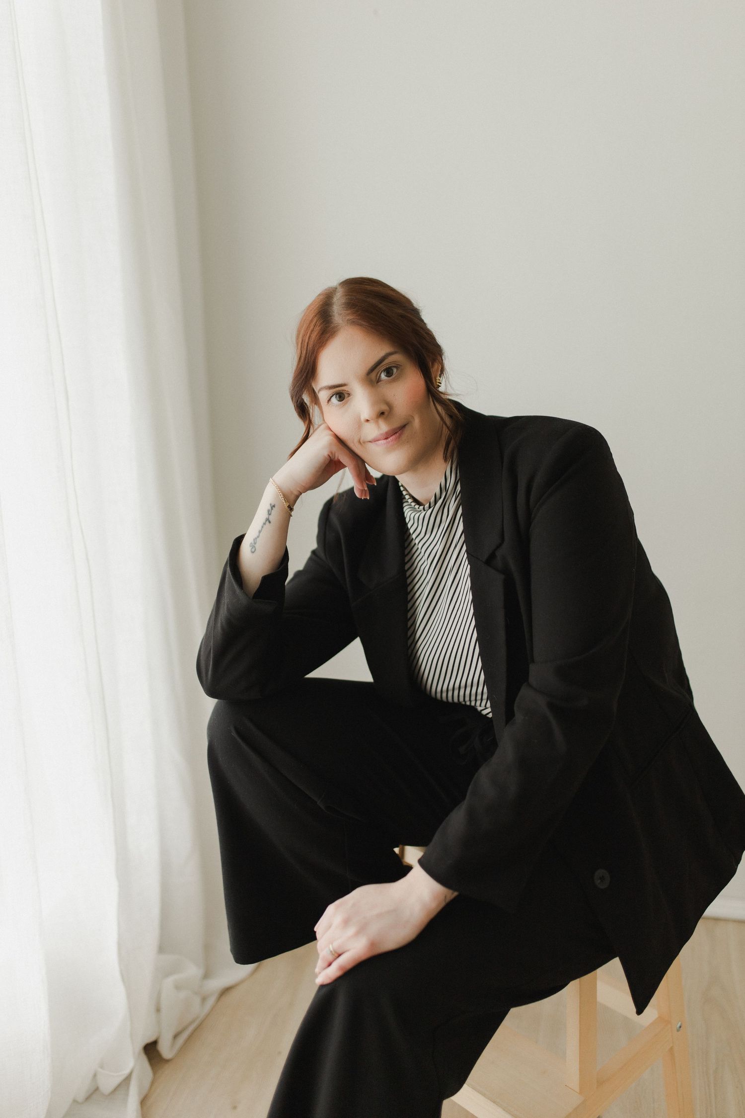 Woman posed on stool with hand on cheek during personal brand photoshoot