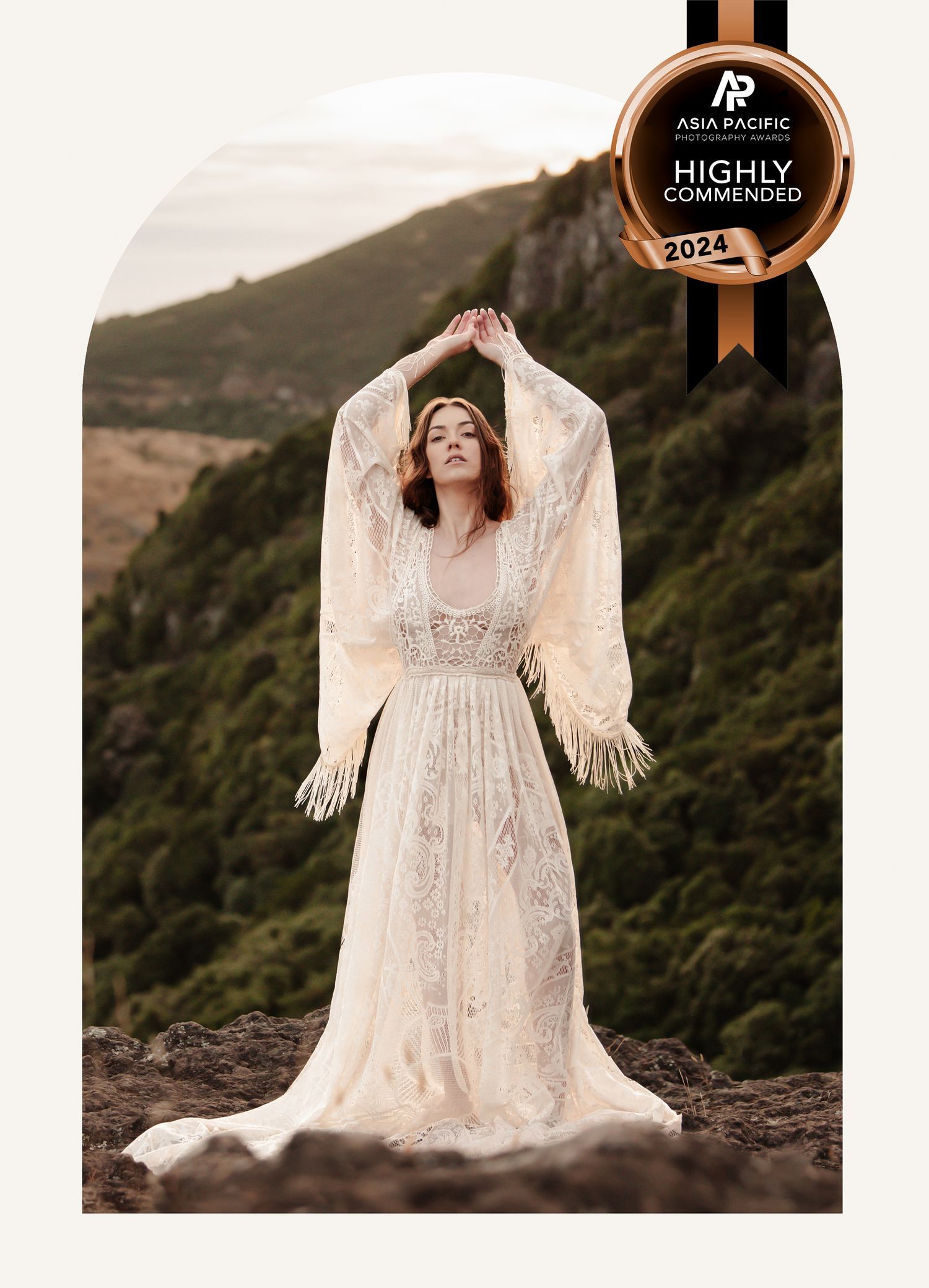 Ethereal bridal portrait in a flowing white lace dress with dramatic angel wings against a misty mountain backdrop.