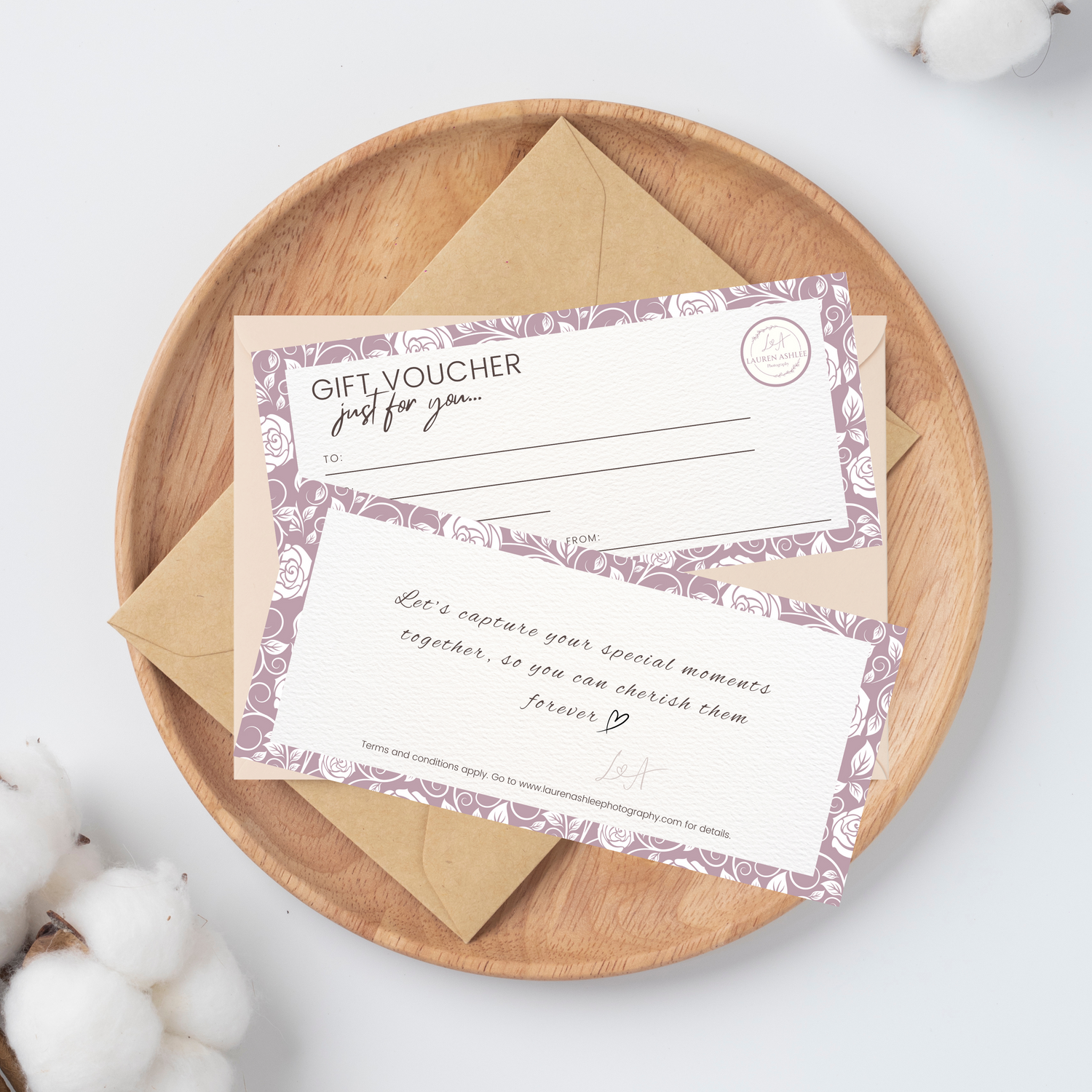 Gift vouchers with floral design displayed on wooden plate with cotton decorations.