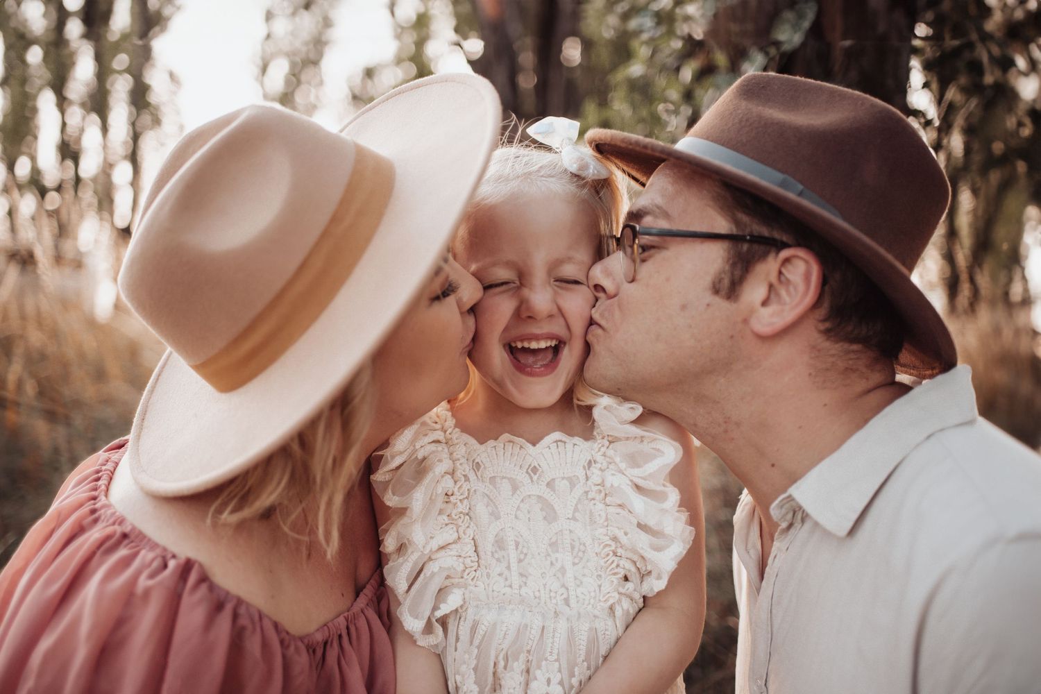 Candid family moment of laughter and kisses in outdoor setting.