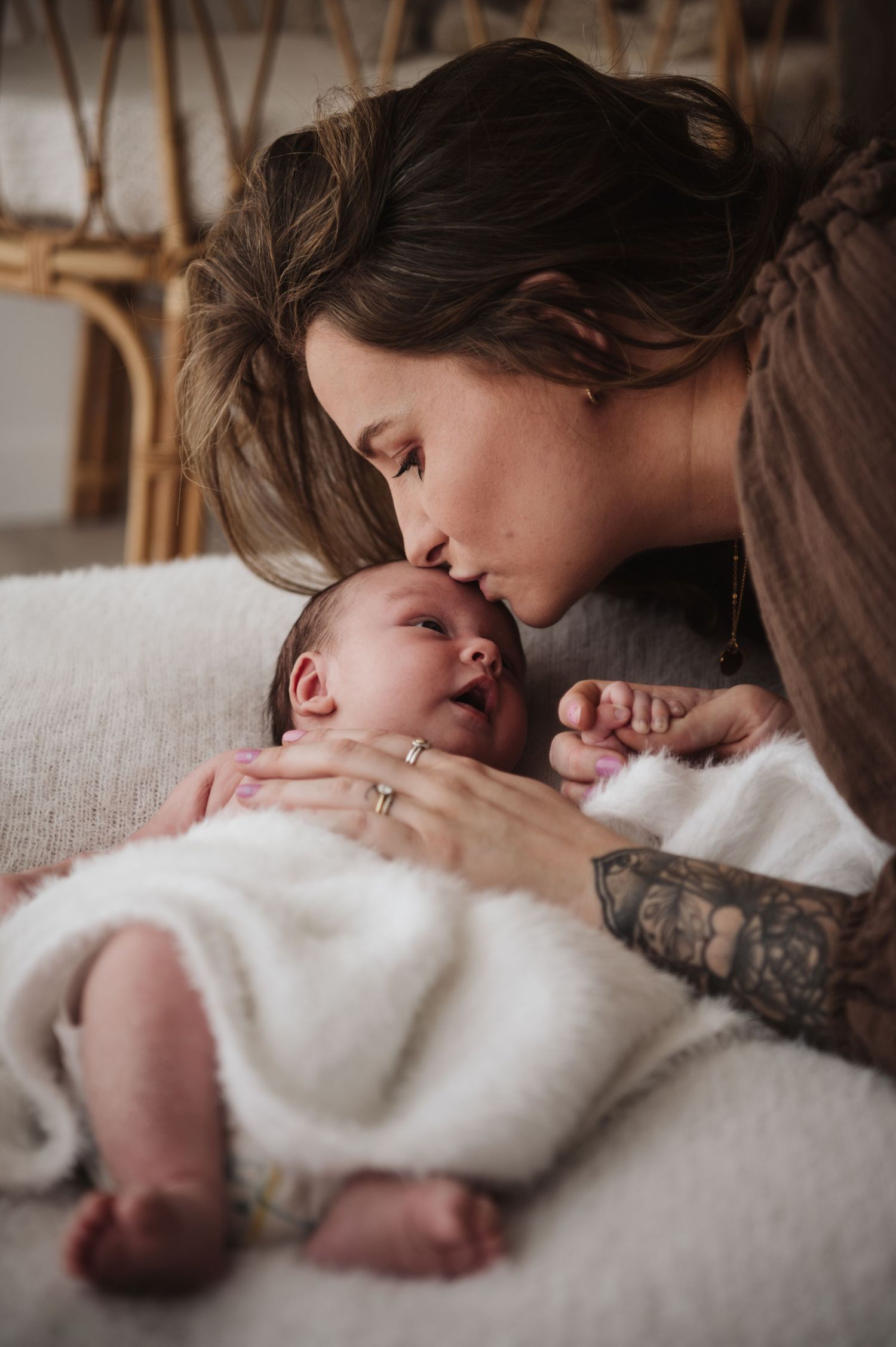 Tender moment between parent and infant on white couch.