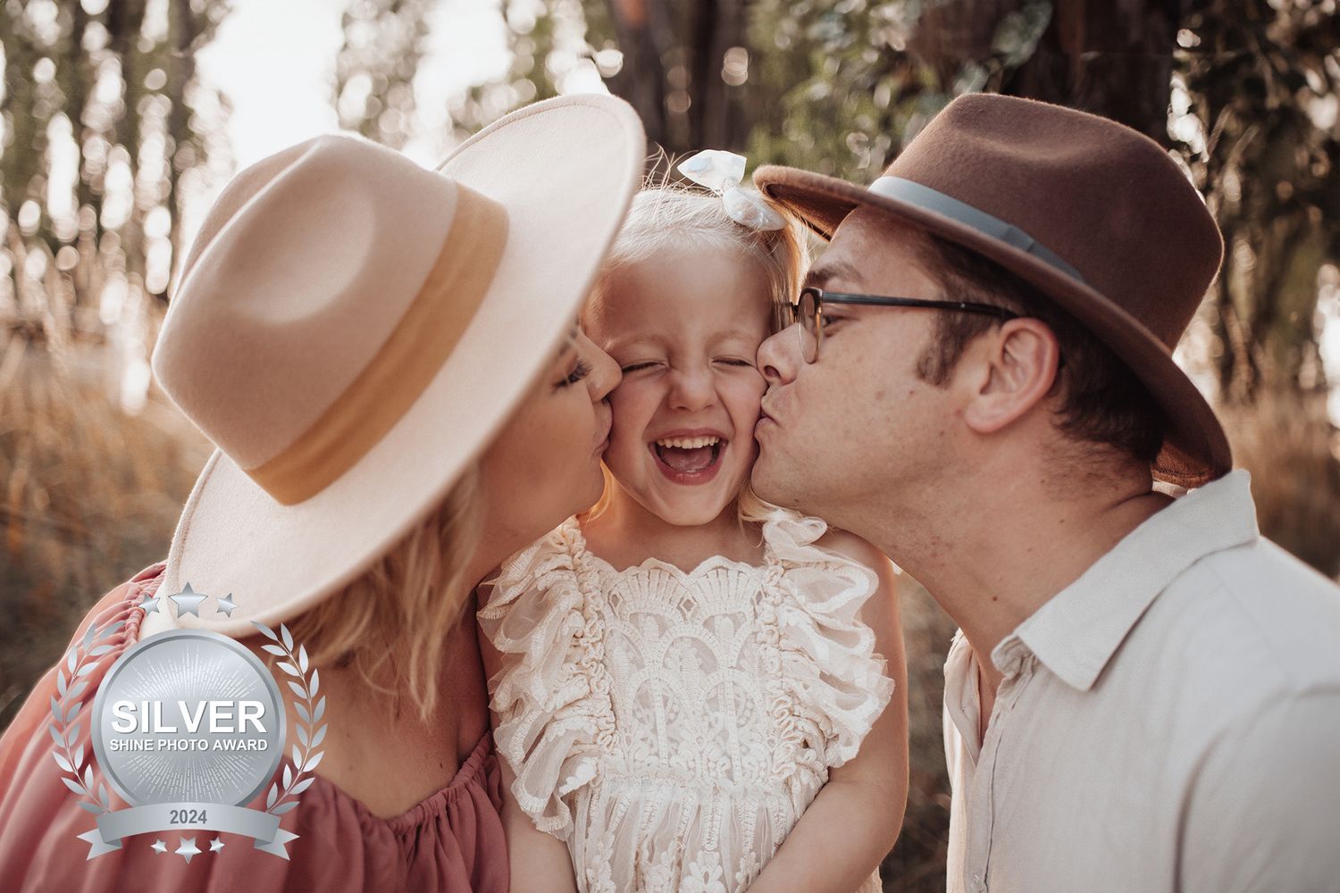A heartwarming family moment captured outdoors with three people sharing laughter and affection in warm sunlight.