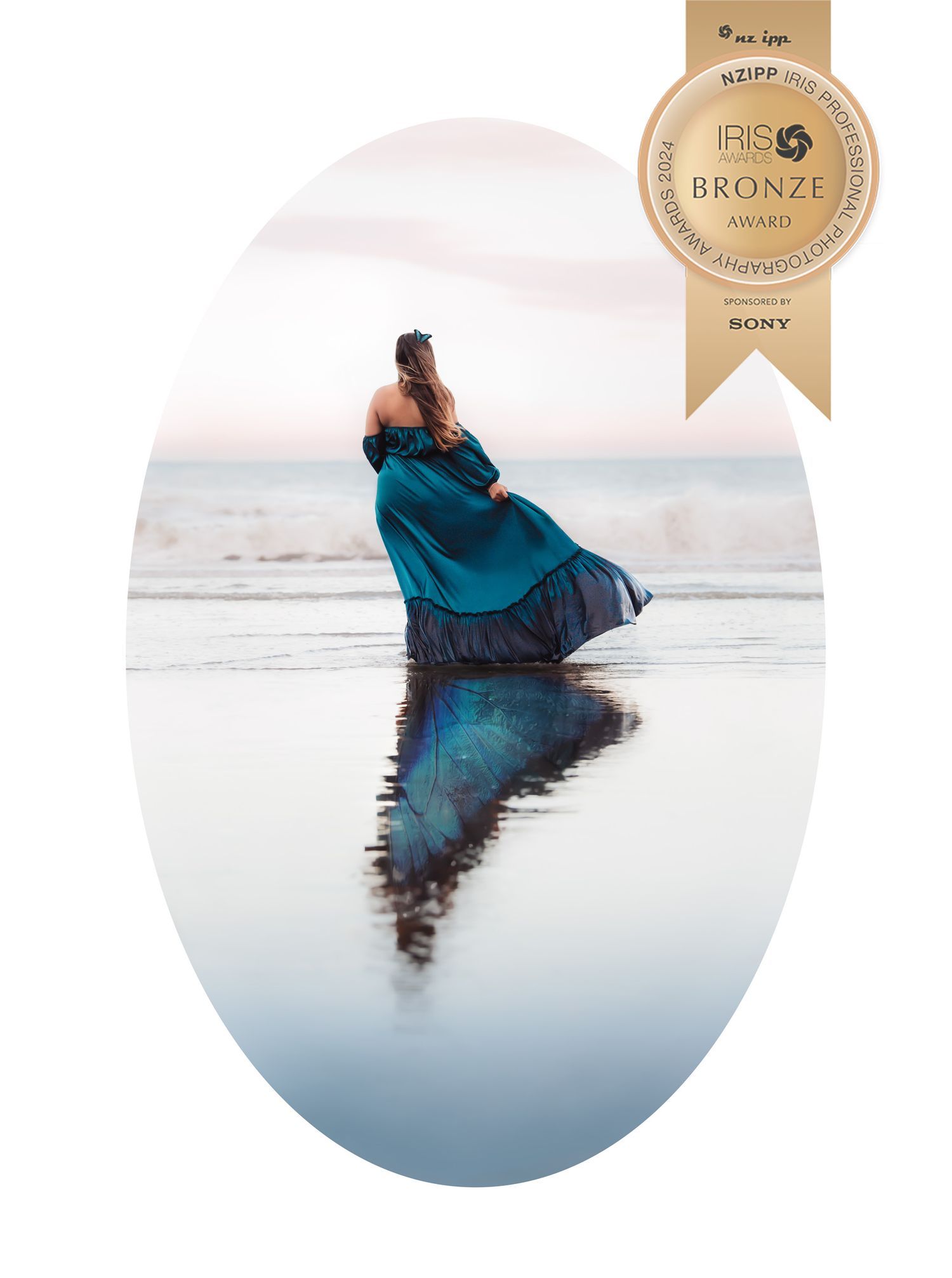 A person in a blue coat stands reflected in calm water at sunset creating a mirror-like symmetrical image.