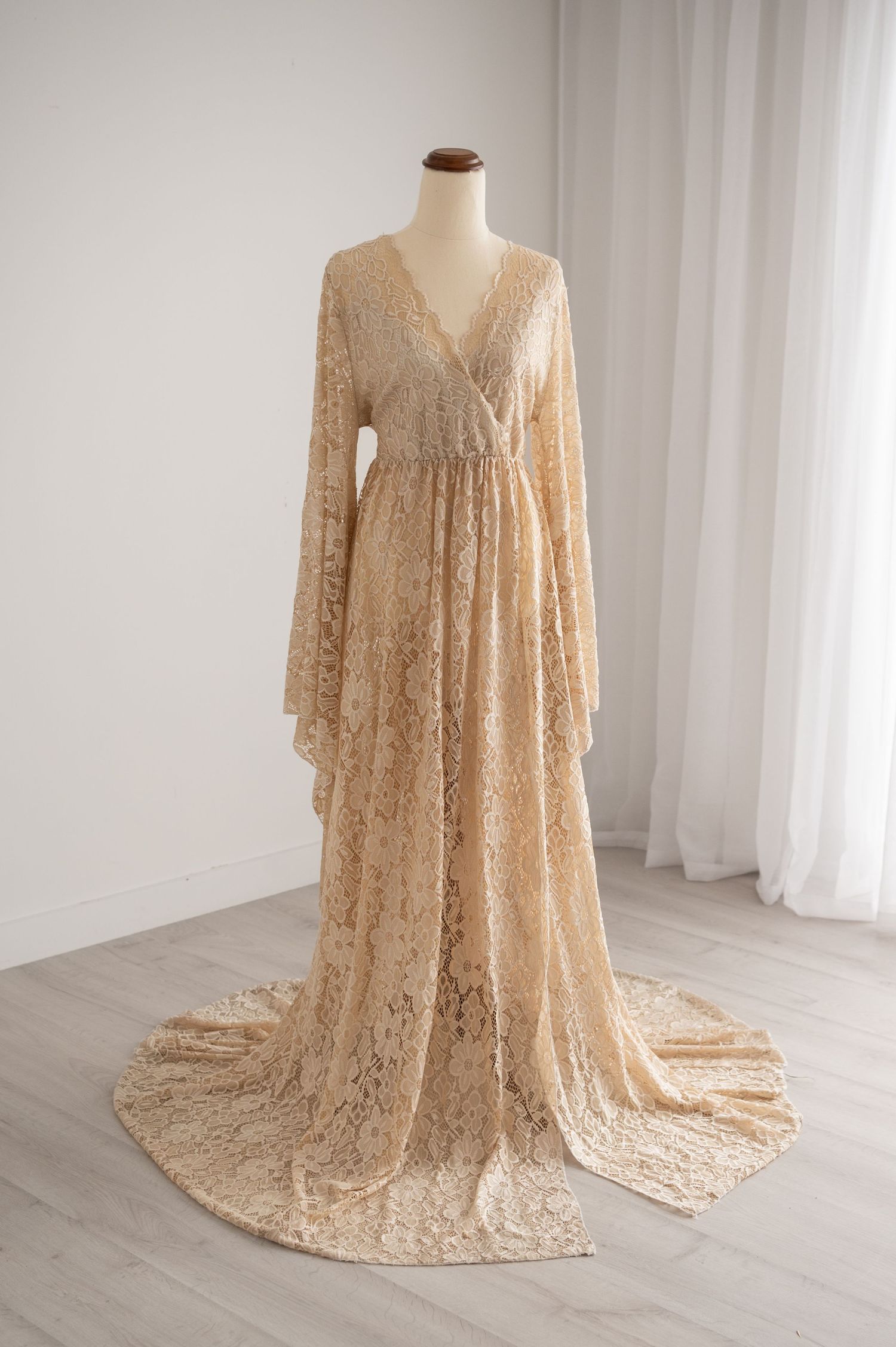 Elegant champagne lace maternity gown with flowing bell sleeves and sweeping train displayed on mannequin from multiple angles.