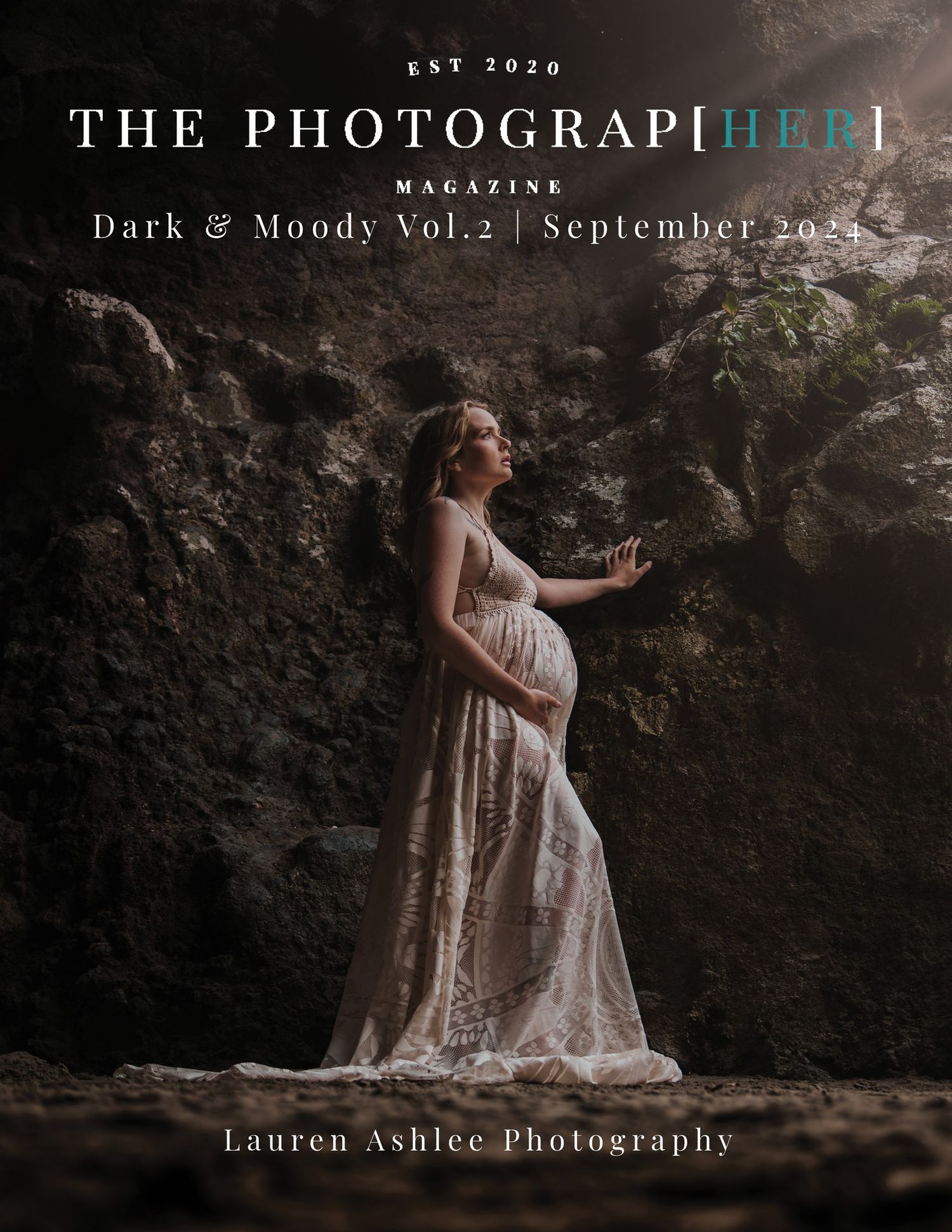 Moody maternity magazine cover showing pregnant woman in lace dress against dark rocky backdrop.